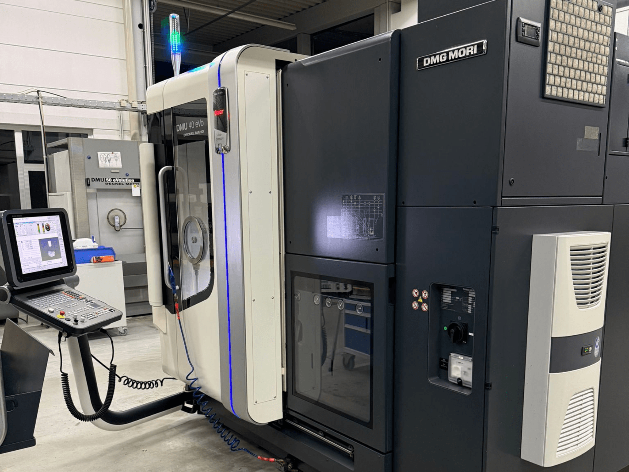 DMG MORI DMU 40 eVo makinesi, kontrolleri, LED göstergeleri ve endüstriyel özellikleri vurgulayan şık tasarımı gösteren önden görünüm.