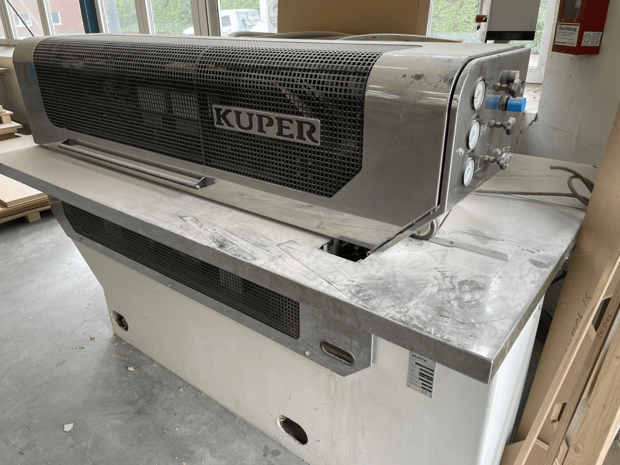 Kaplama giyotini KUPER FLI, önden görünüm, paslanmaz çelik gövde, göstergeler ve tezgah üzerinde temiz bir kesim alanına sahiptir.