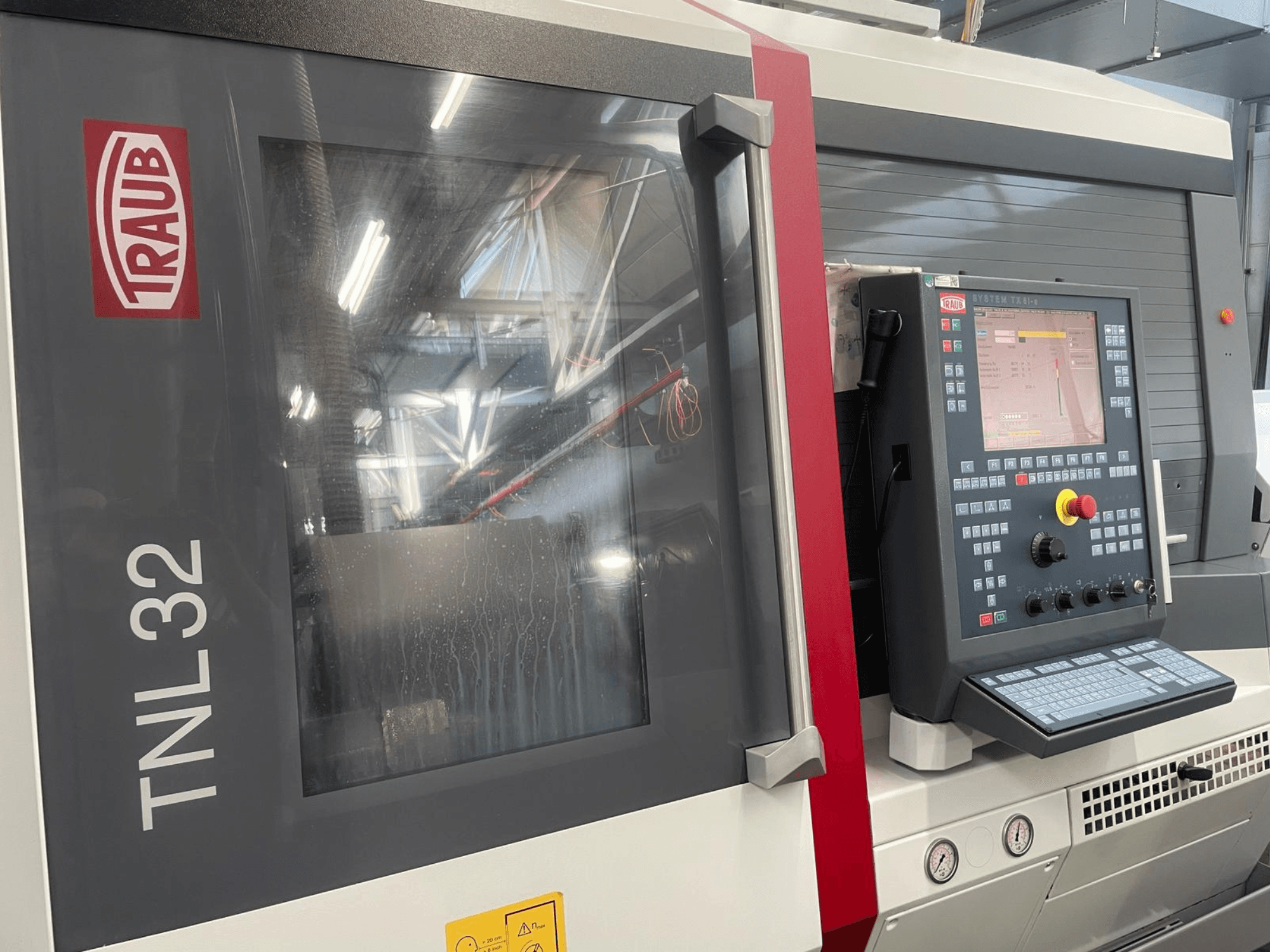 Traub TNL32 CNC torna tezgahının önden görünümü, düğmeli kontrol paneli, ekran ve şık metal kasa.
