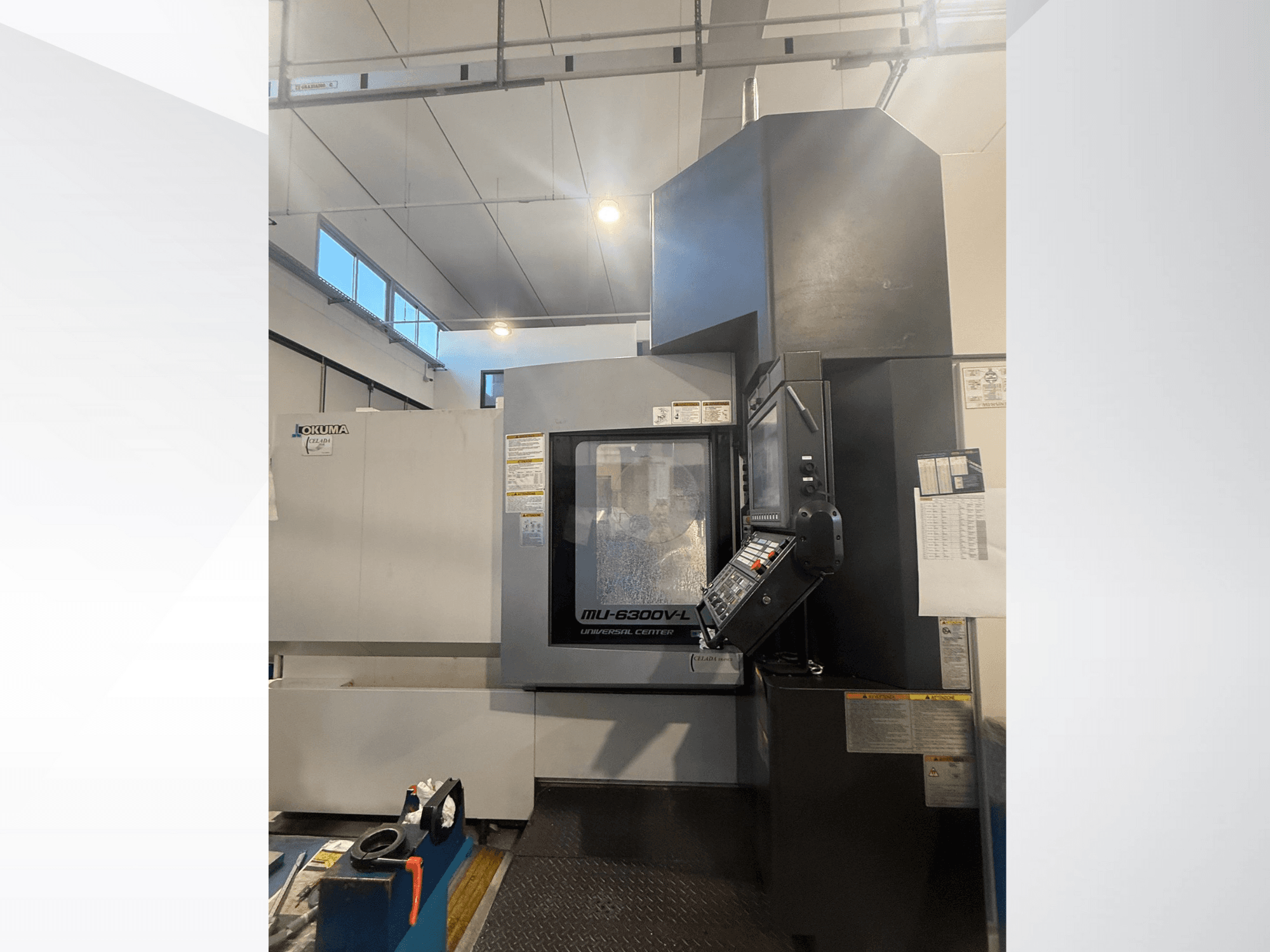 Okuma MU-6300V-L CNC makinesi önden bakıldığında kontrol panelini ve güvenlik etiketlerini gösterir.