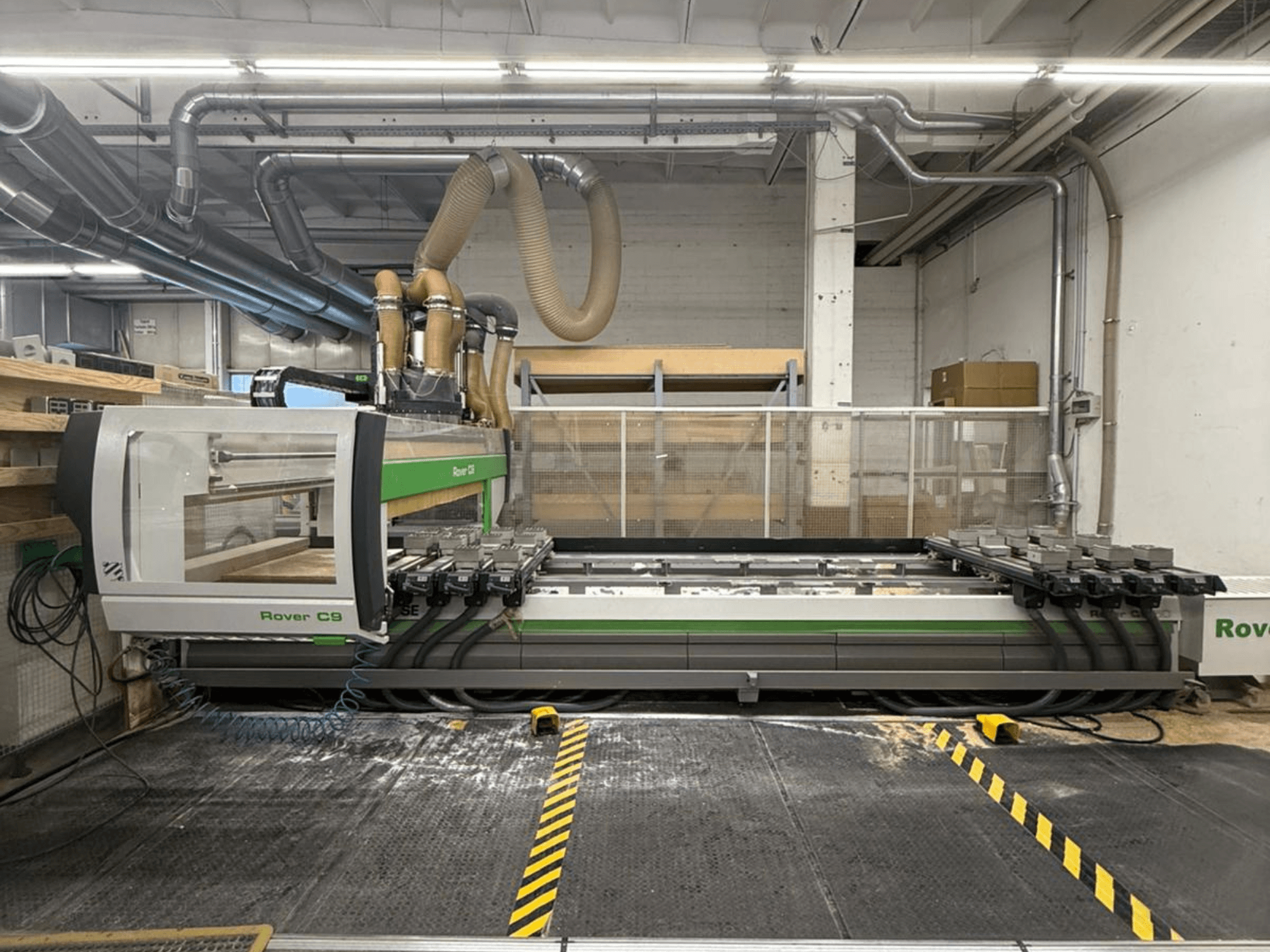 Atölyedeki Rover C9 CNC makinesi, önden görünüm, çoklu kesme kafaları ve görünür toz emme sistemi.