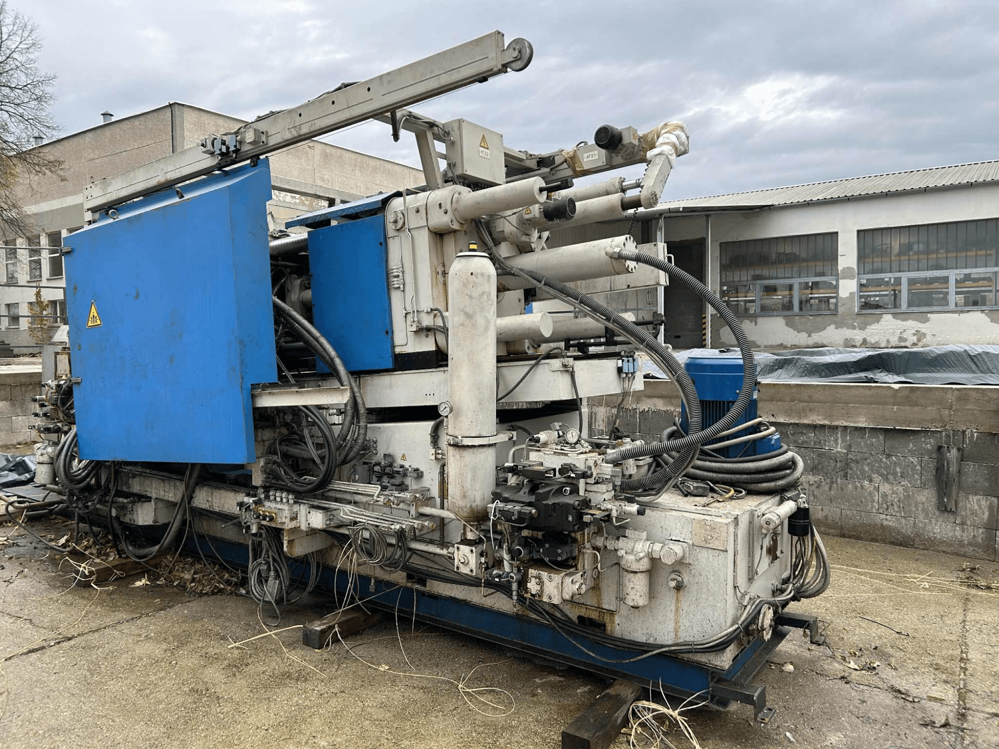 Mavi gövdeli, çeşitli hortumlara ve metal bileşenlere sahip büyük endüstriyel hidrolik makine, yandan görünüm.