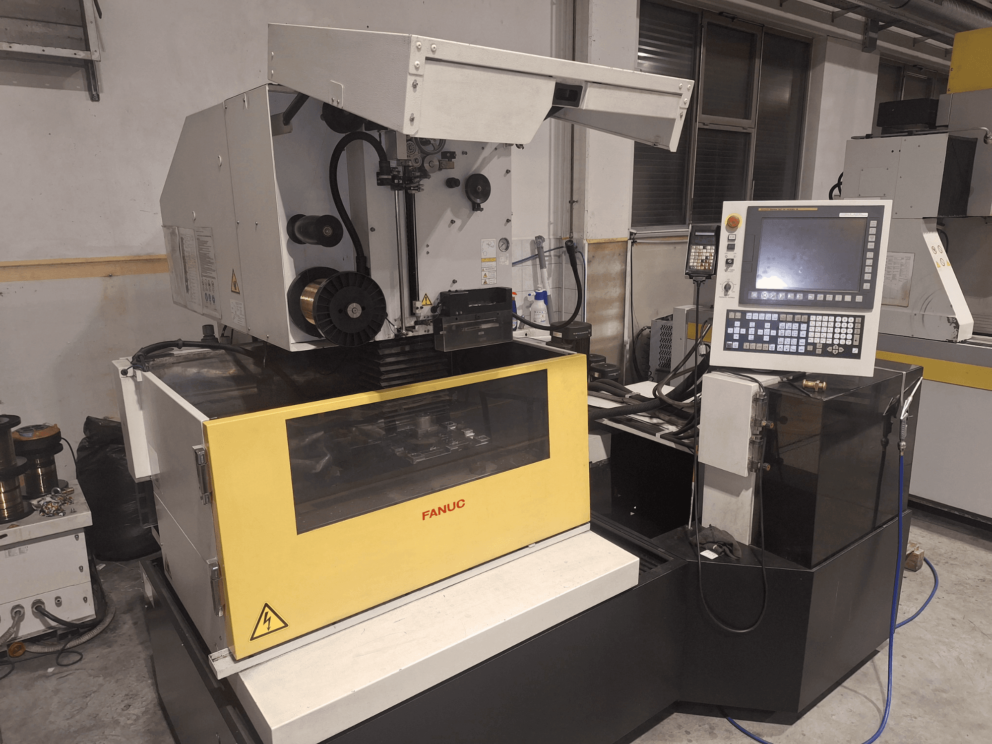 FANUC CNC makinesi, çalışma alanını ve sağdaki kontrol panelini ortaya çıkaran açık kapaklı ön görünümde.