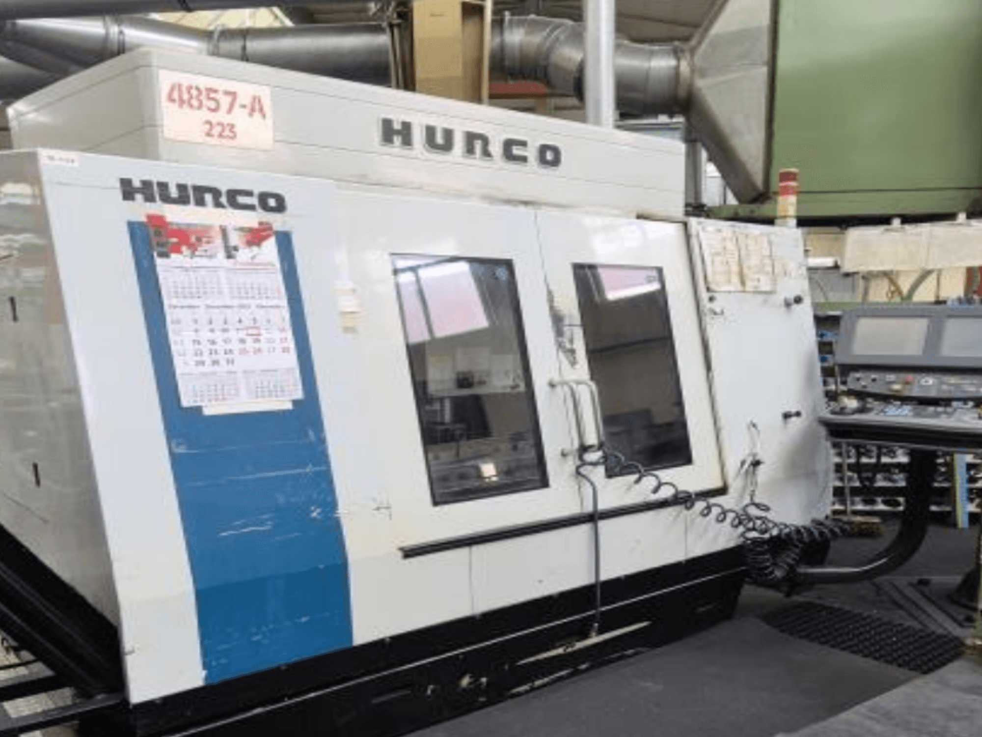 Hurco VMX 42 dikey işleme merkezinin önden görünümü, kontrol paneli, takvim ve metal dış detaylar.