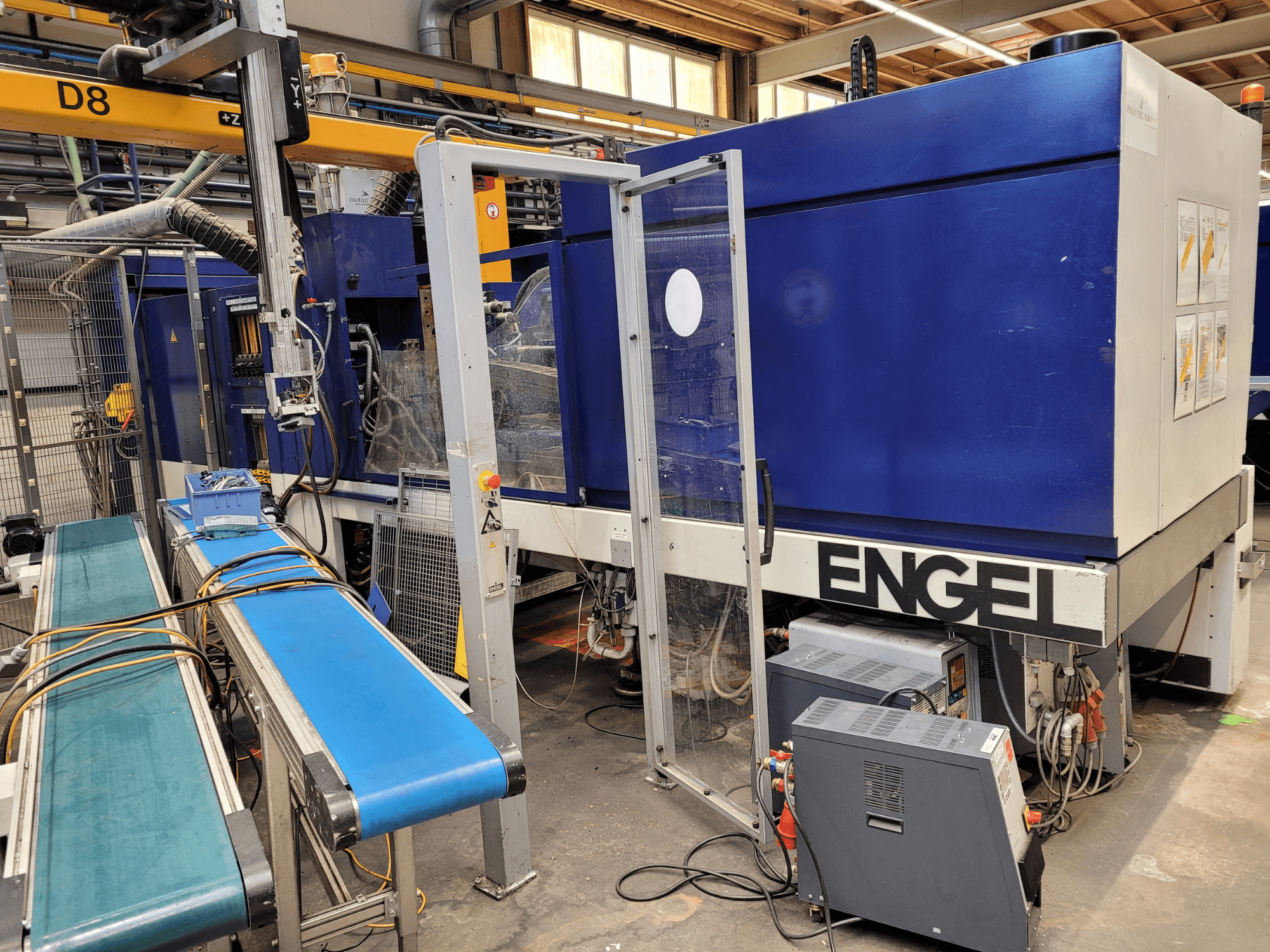 Şeffaf güvenlik kapılı, yandan görünümlü, kontrol panelli, konveyör bantlı ve görünür elektrik bağlantılarına sahip mavi ENGEL makinesi.