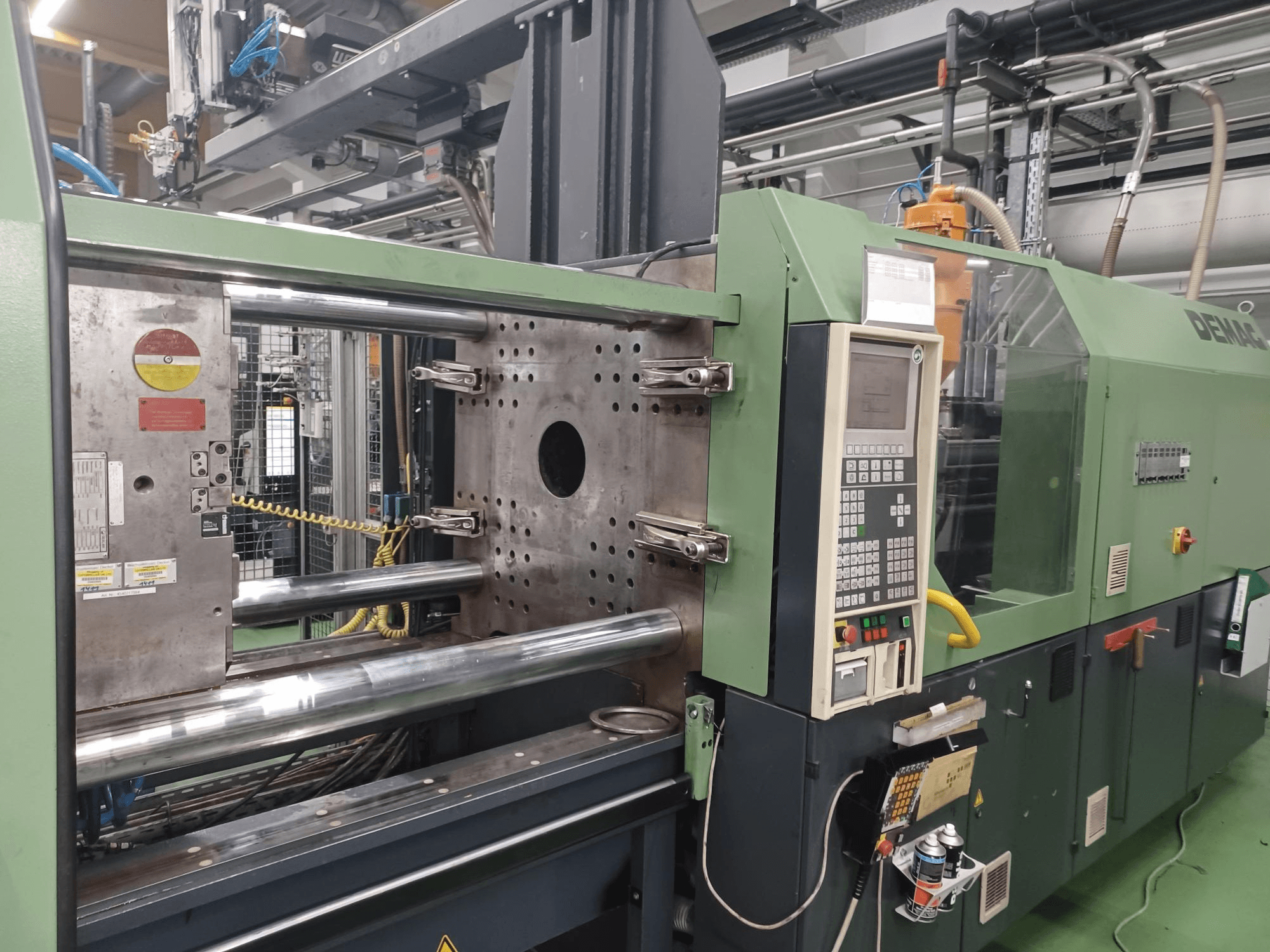 Demag enjeksiyon kalıplama makinesi, önden görünüm, kontrol paneli, metalik hidrolik silindirler ve güvenlik özellikleri.