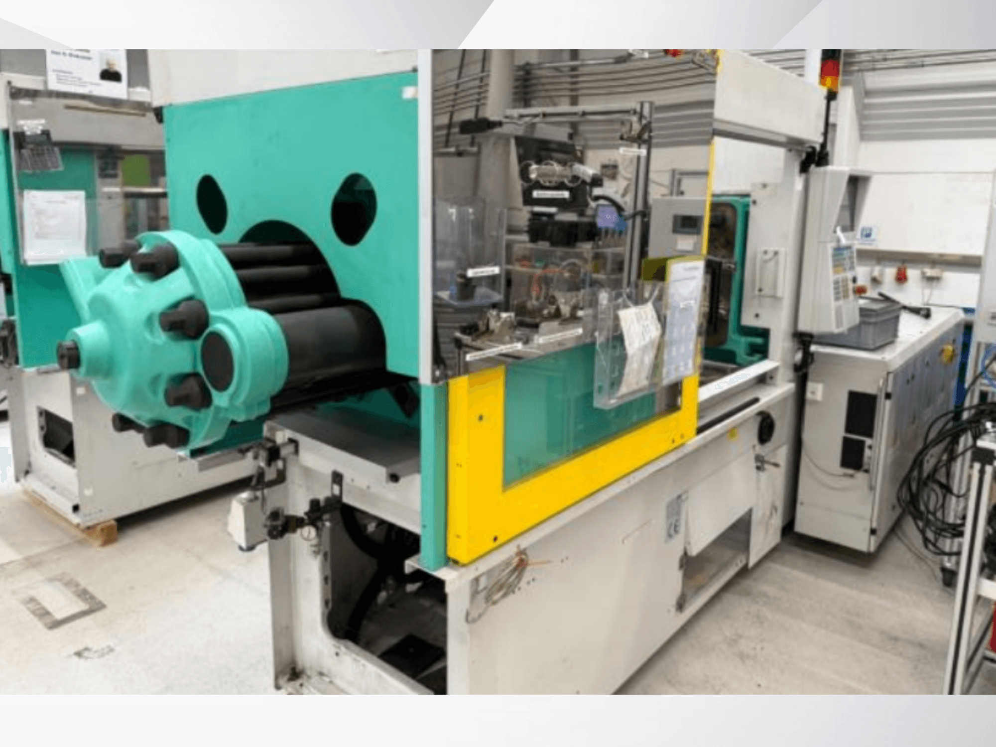 Enjeksiyon kalıplama makinesi, açık mavi ve sarı, önden görünüm, görünür bir kalıp ve etiketli kontrol paneli.