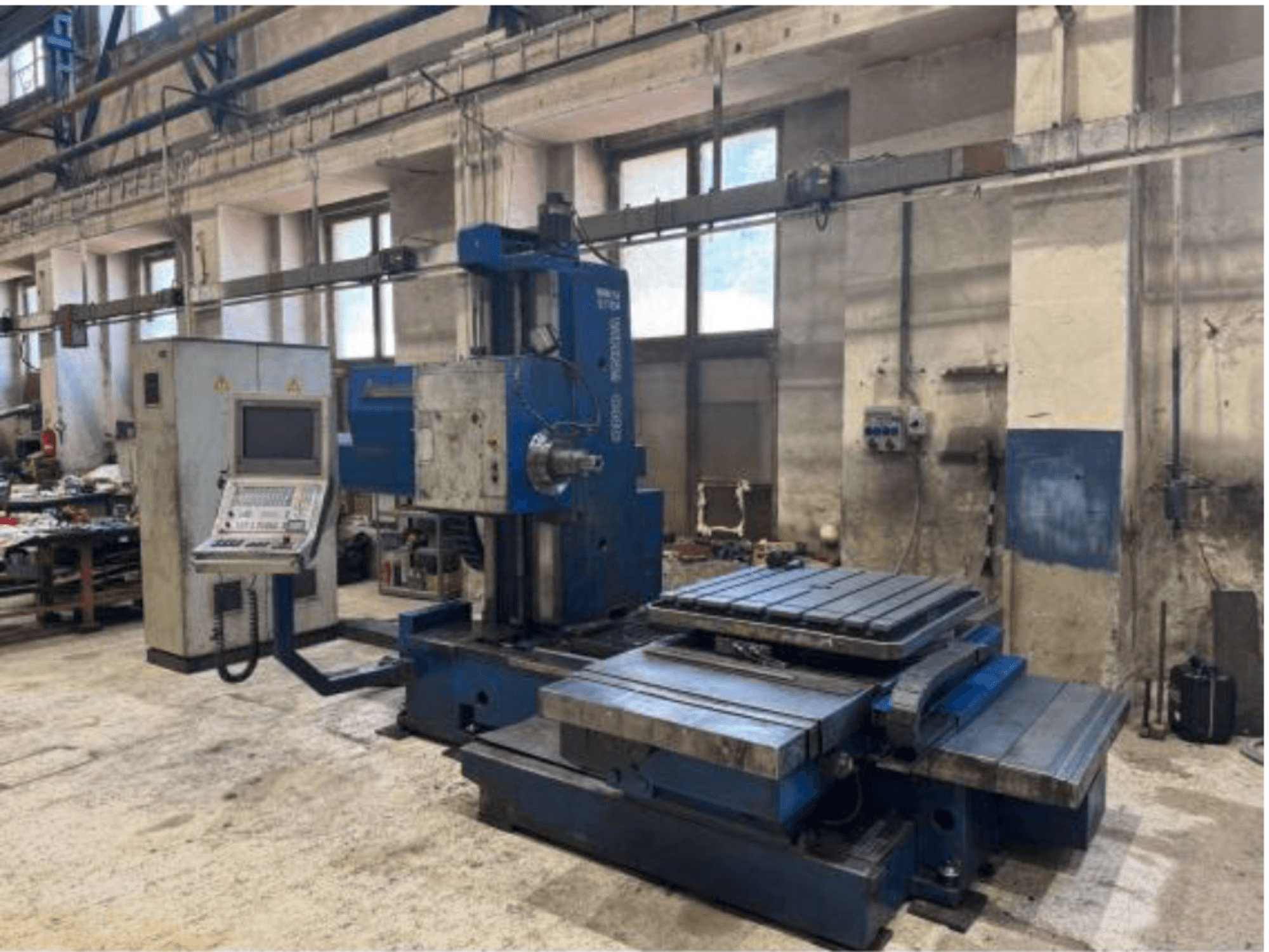 TOS WHN 9 B CNC delme makinesinin önden görünümü; kontrol paneli ve geniş çalışma masası ile donatılmış, bir atölye ortamında yer almaktadır.