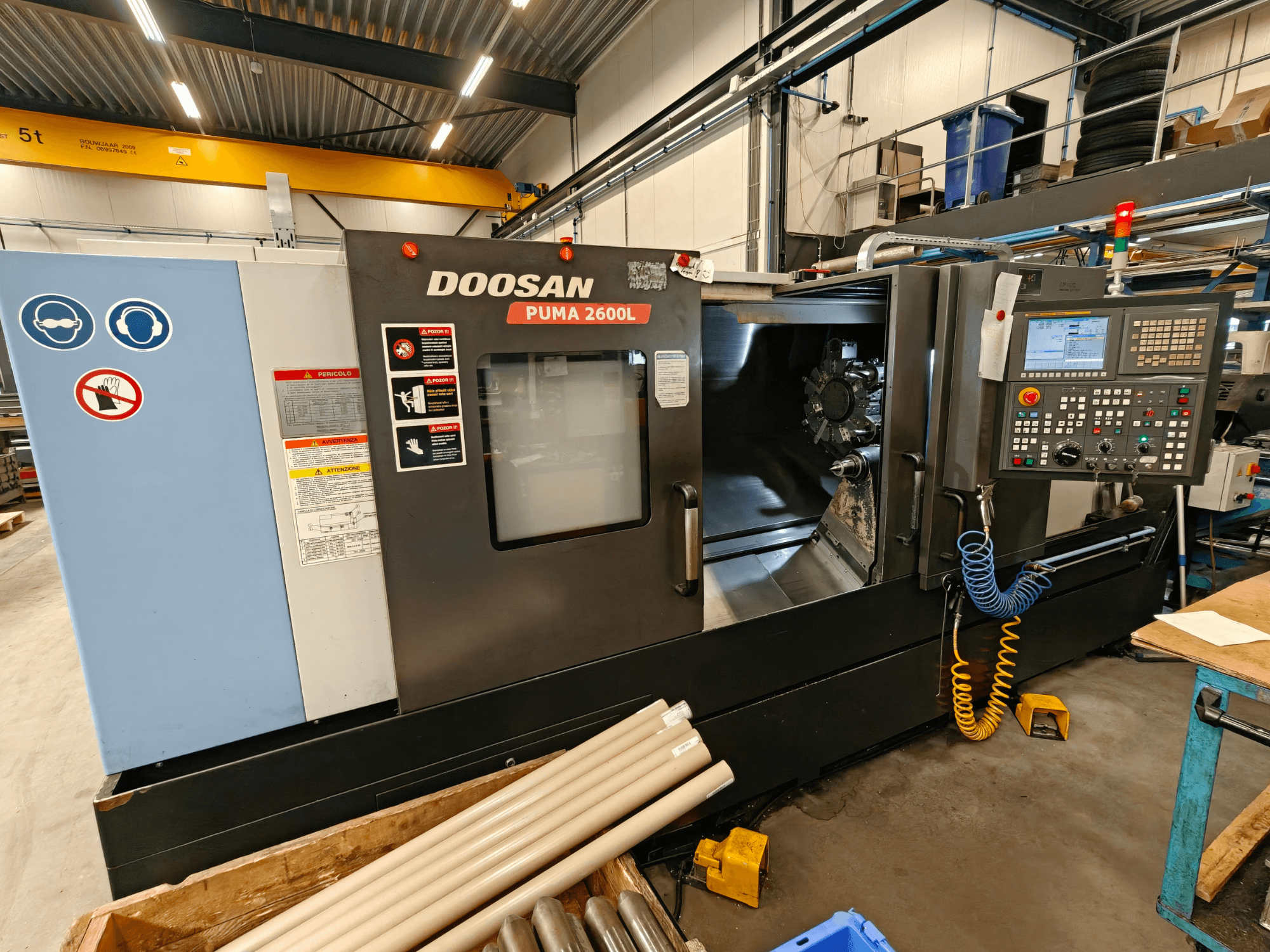 DOOSAN Puma 2600L yatay torna makinesi atölyede, kontrol paneli ve iş mili alanını gösteren yandan görünüm.