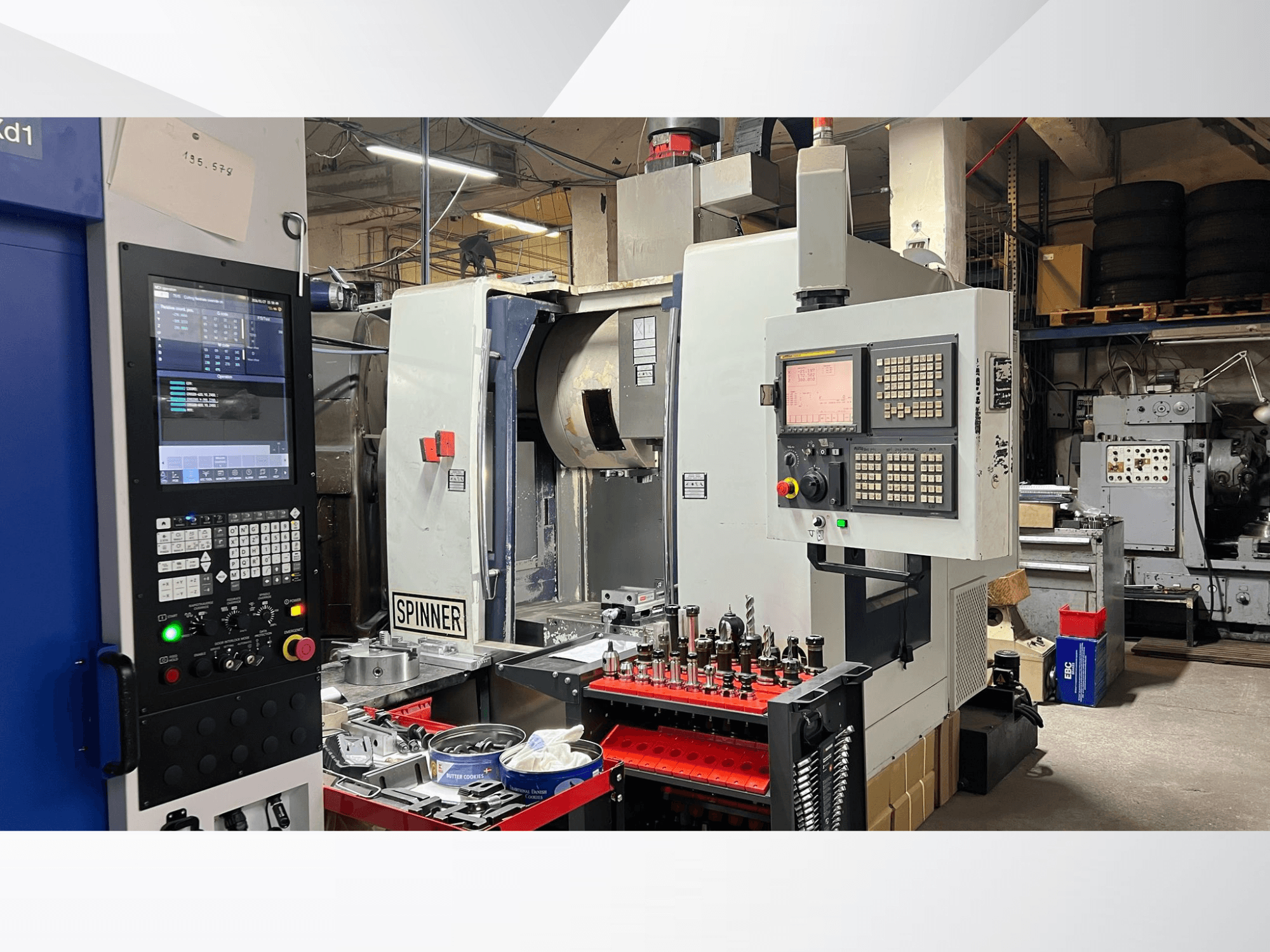 Bir atölye ortamında ön açıdan bakıldığında kontrol paneli, aletler ve iş parçalarının görülebildiği CNC makinesi.