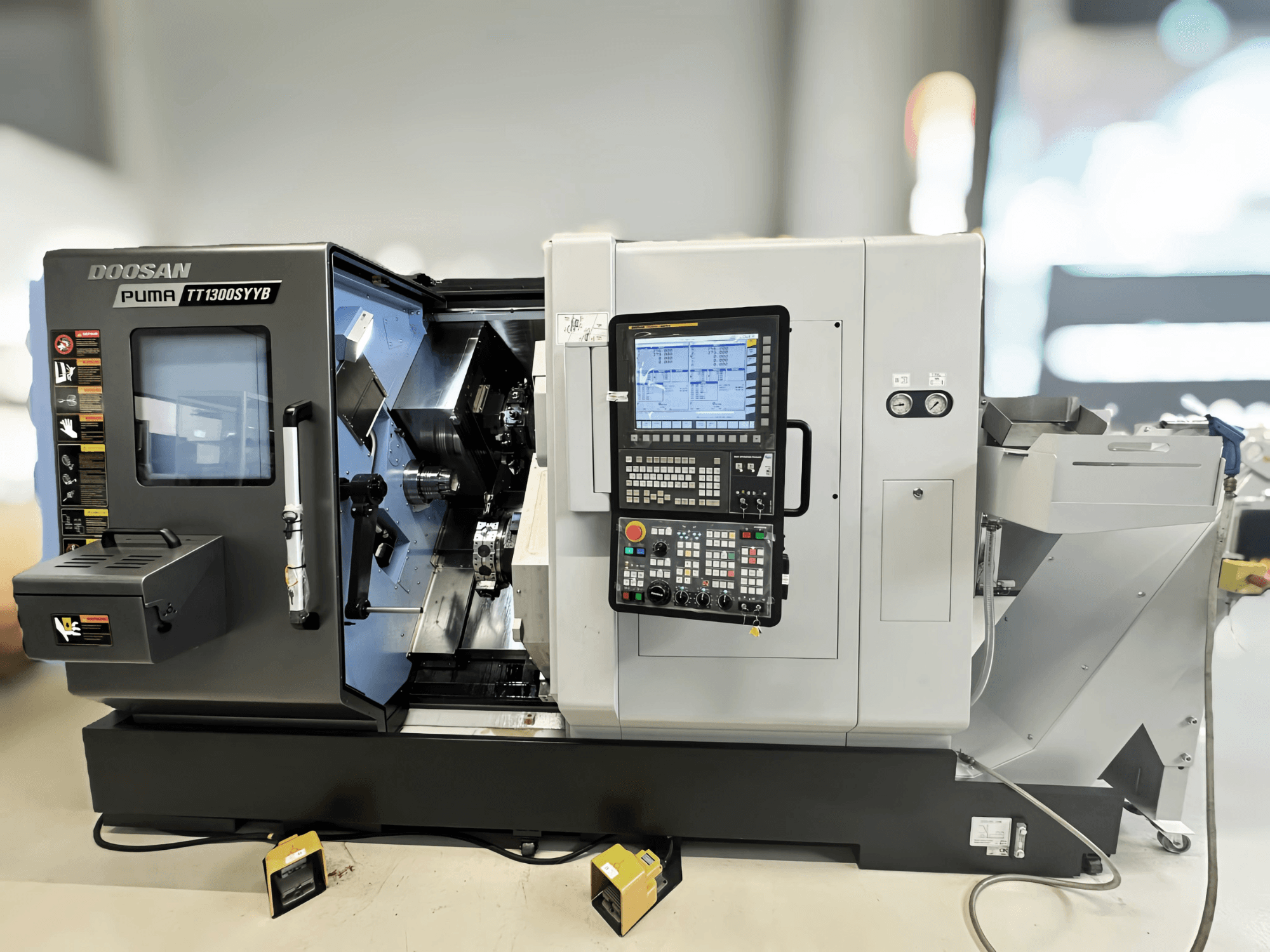 Doosan Puma TT1300SYYB torna freze merkezinin yandan görünümü, kontrol paneli ve makinenin iç kısmı, aletler görünür şekilde.