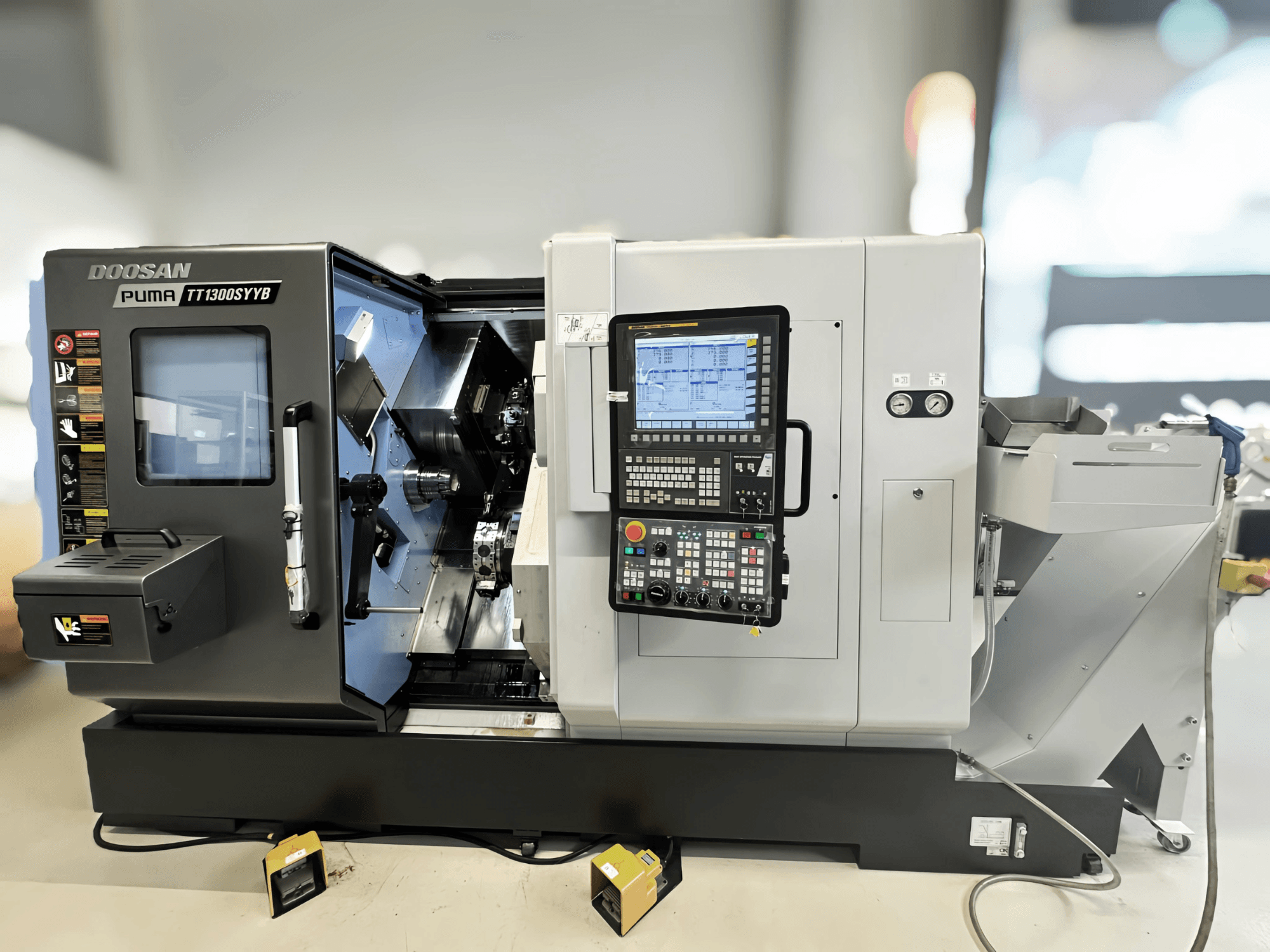 Doosan Puma TT1300SYYB torna freze merkezinin yandan görünümü, kontrol paneli ve makinenin iç kısmı, aletler görünür şekilde.