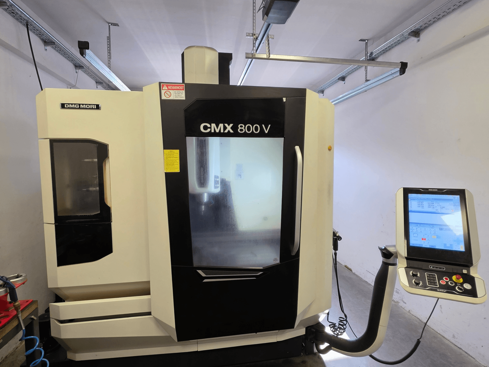 DMG MORI CMX 800V dikey işleme merkezi, önden görünüm; dokunmatik ekranlı kontrol paneli ve açık ve net güvenlik işaretleri ile donatılmıştır.
