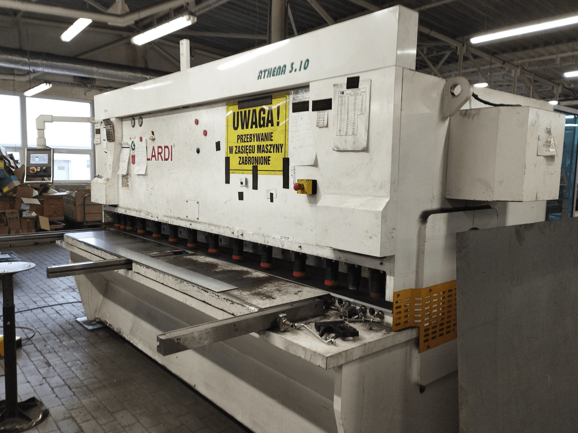 Bir atölyede bulunan GILARDI ATHENA 3.10 CNC Kesme Makinesi, önden görünüm; kontrol paneli ve kesme bıçakları görülmektedir.