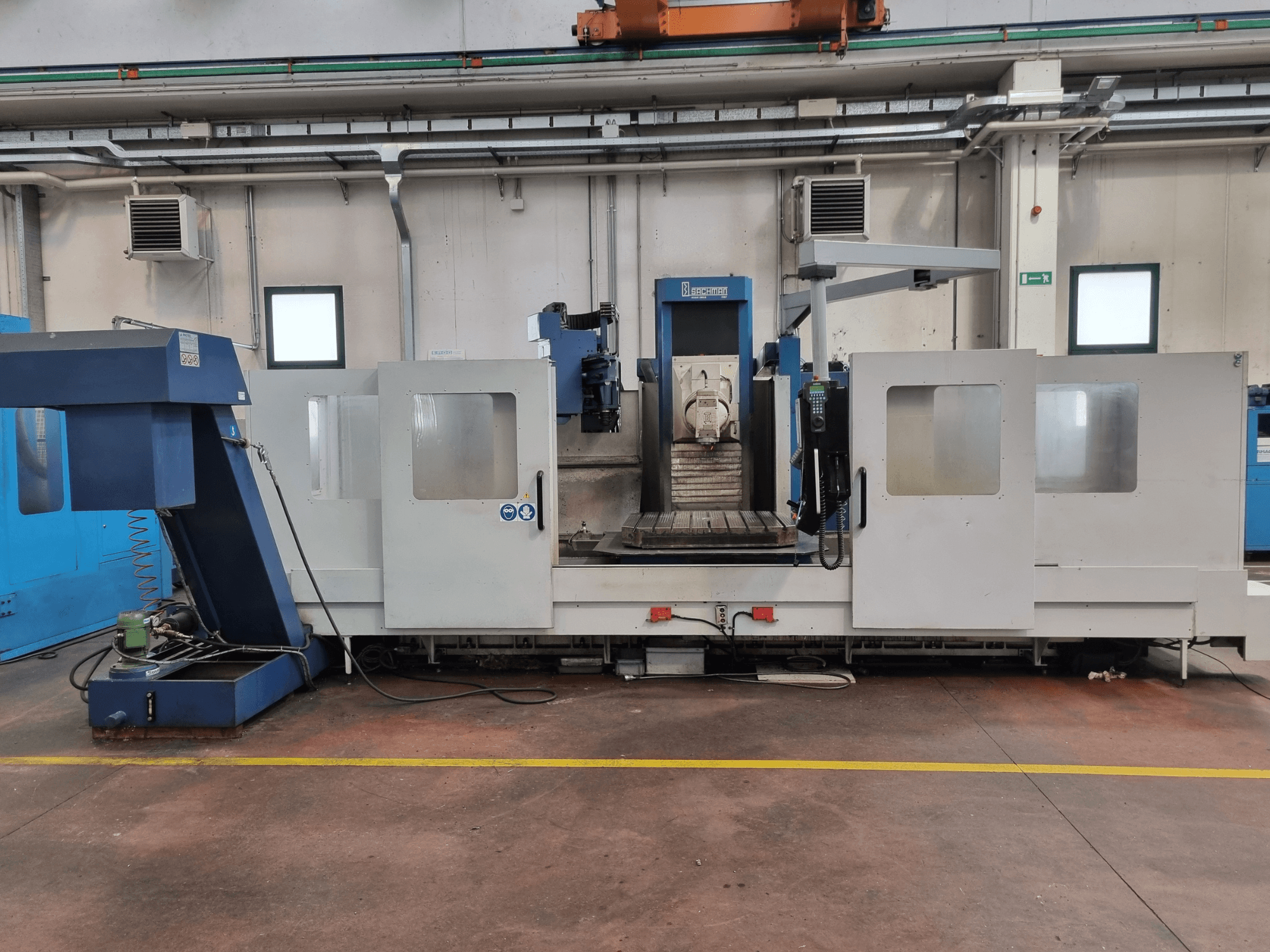 "Brembana" CNC freze makinesi, kontrol panelini ve içinde bir çalışma masası bulunan çalışma alanını gösteren yandan görünüm.