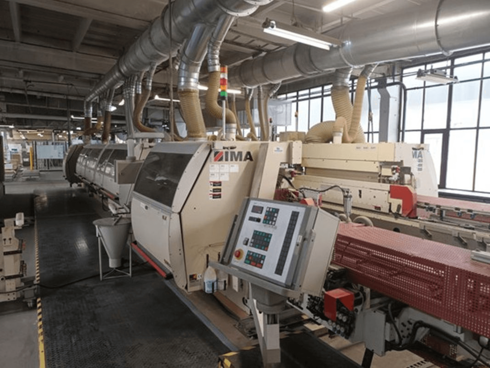 Fabrika ortamında IMA endüstriyel makineleri, önden görünüm, kontrol panelleri ve toz emme boruları.