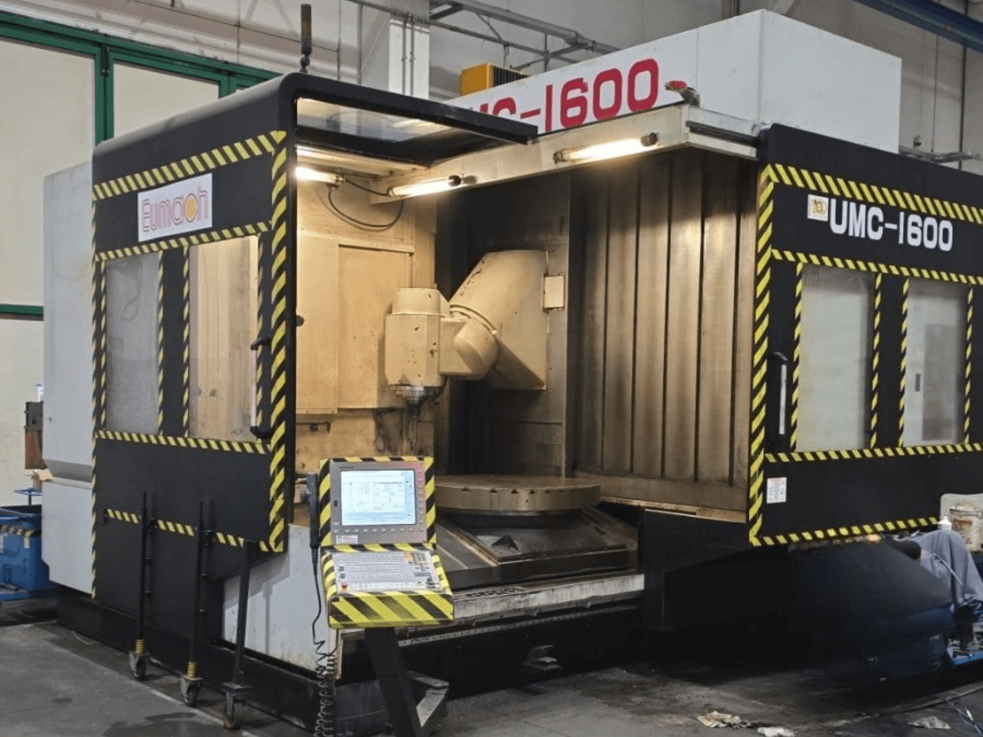 Eumach UMC-1600 dikey işleme merkezi; kontrol panellerini ve güvenlik şeritleriyle işaretlenmiş işleme alanını gösteren önden görünüm.