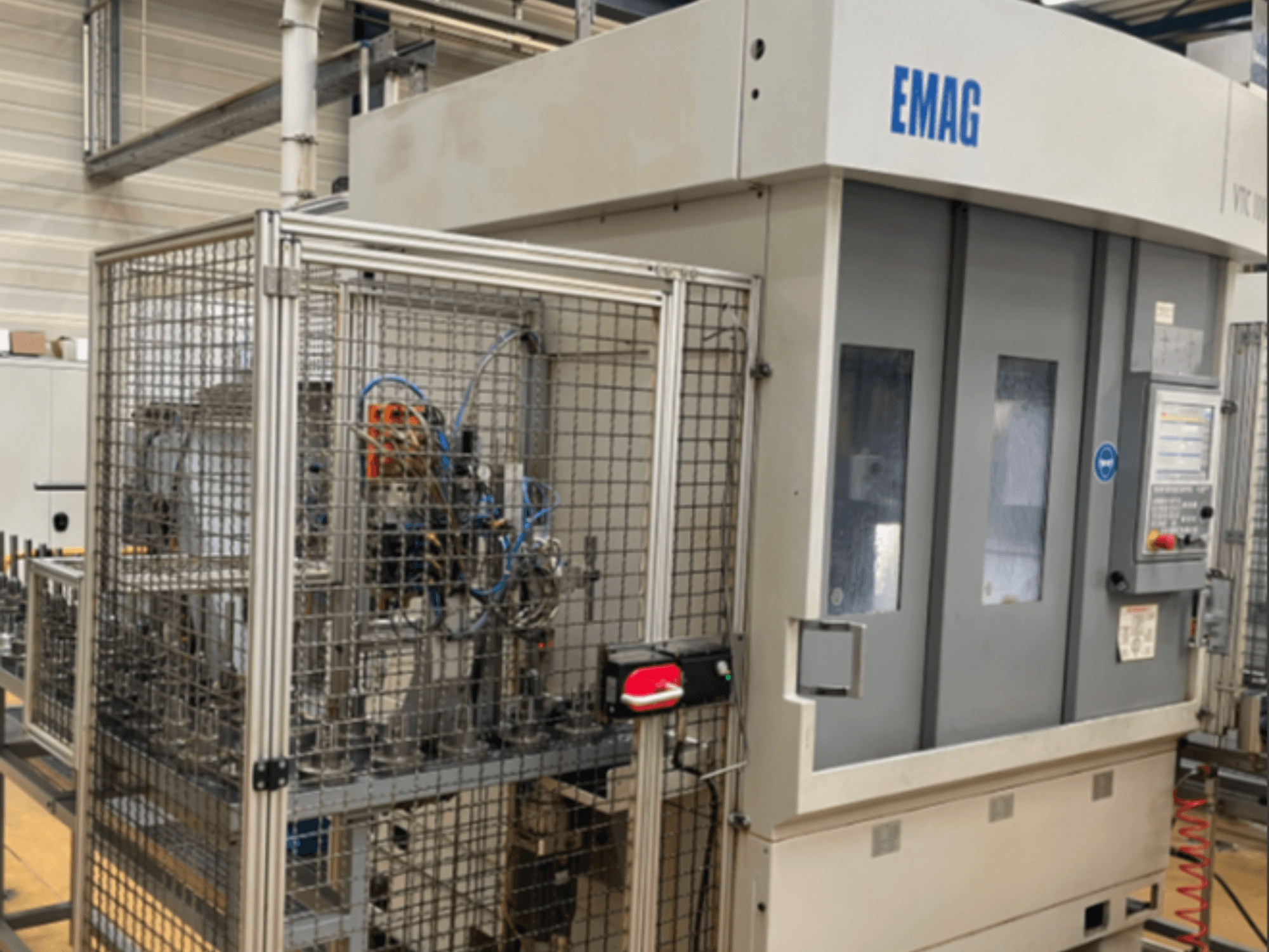 EMAG VTC 100 dikey torna tezgahının yandan görünümü; kontrol paneli ve güvenlik çitlerinin detayları gösterilmektedir.