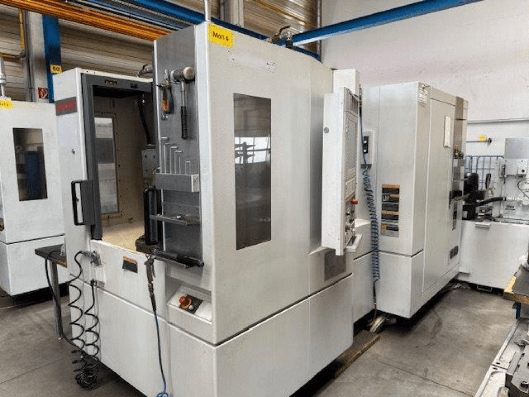 MORI SEIKI NH4000 DCG yatay işleme merkezi, açık bir kapı ve kontrol paneli detaylarıyla önden gösterilmiştir.