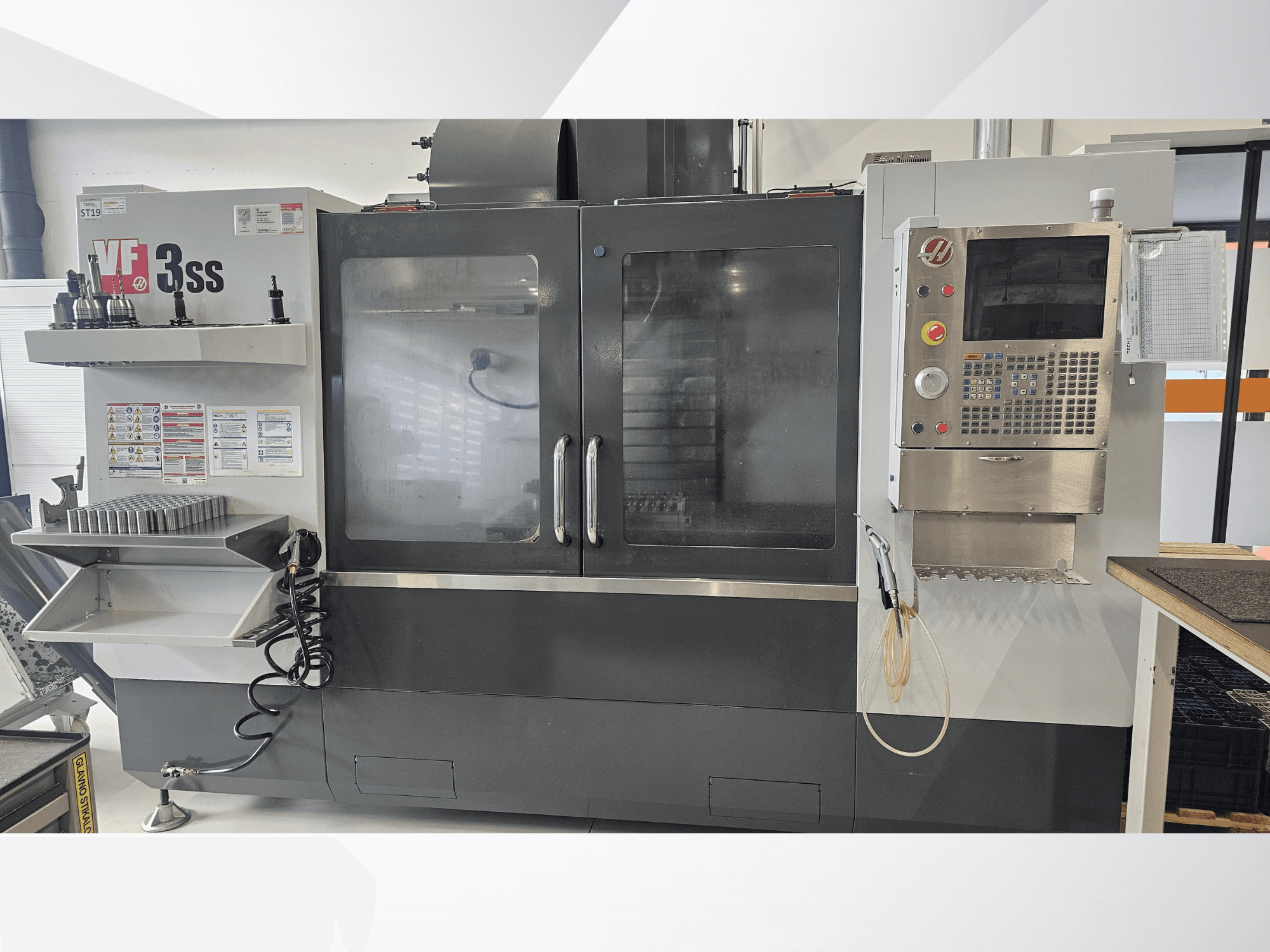HAAS VF-3SS dikey işleme merkezi, önden görünüm, kontrol paneli, takım rafı ve büyük cam kapı.