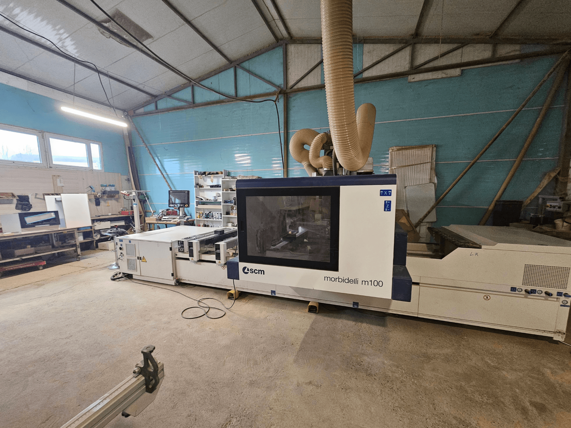 Bir atölyede SCM Morbidelli M100 CNC makinesi, önden görünüm, toz emme sistemi ve kontrol paneli.