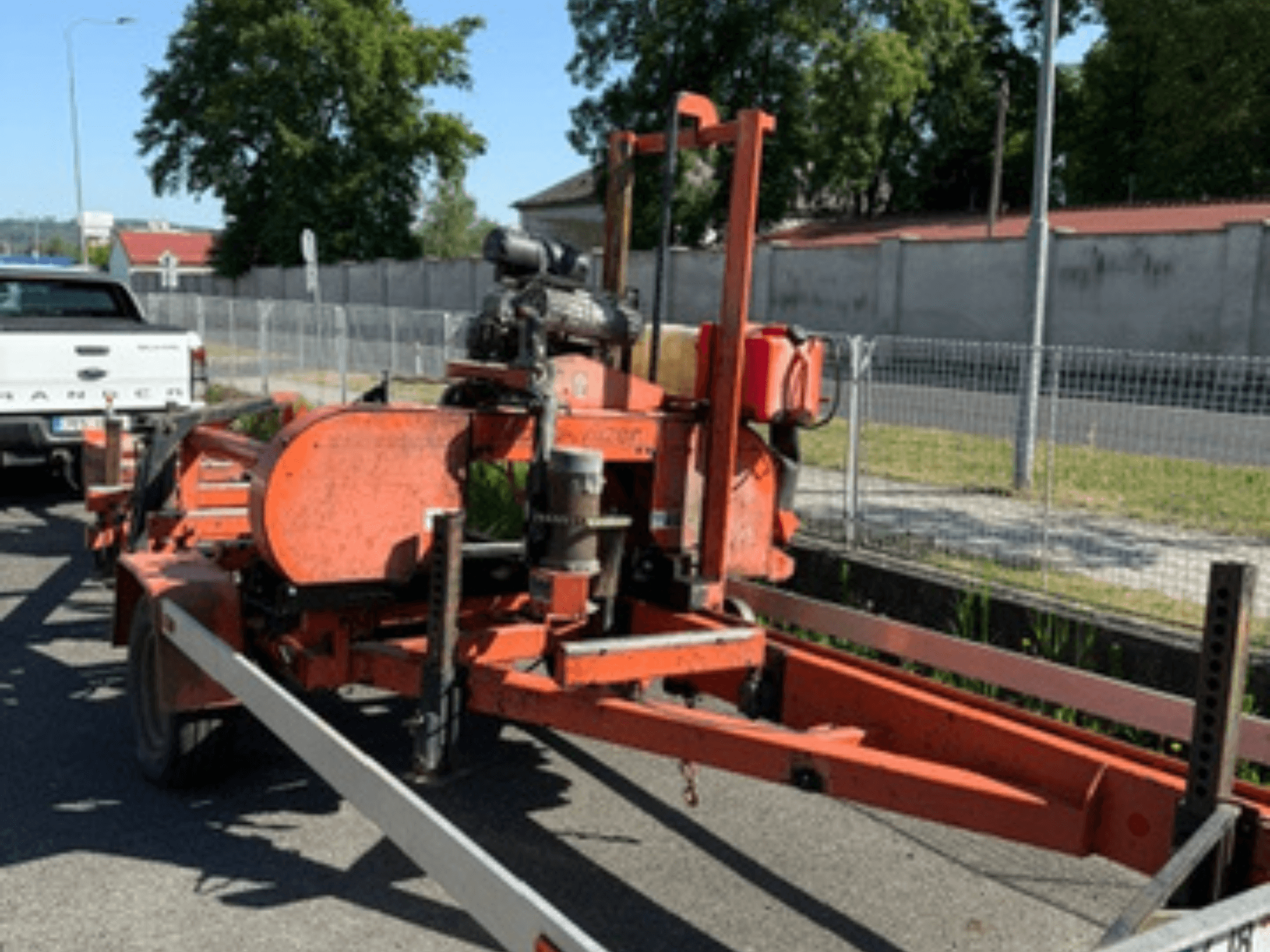 Turuncu renkli WOOD-MIZER LT40 ahşap şerit testere; tekerlekleri ve motor parçaları görülebilen bir römork üzerinde yan görünüm.