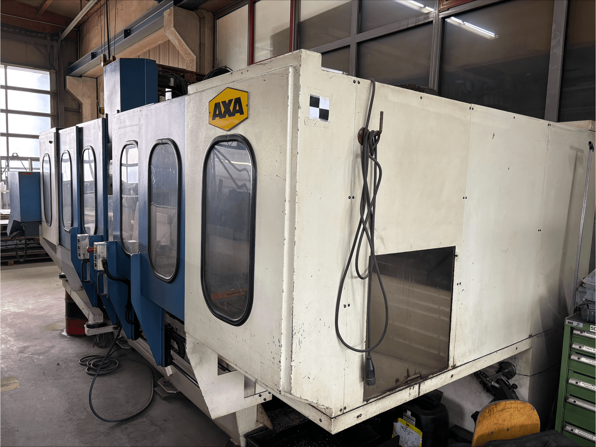 AXA VSC-1-M/C dikey işleme merkezi, önden görünüm, büyük beyaz kabin ve mavi kontrol paneli.