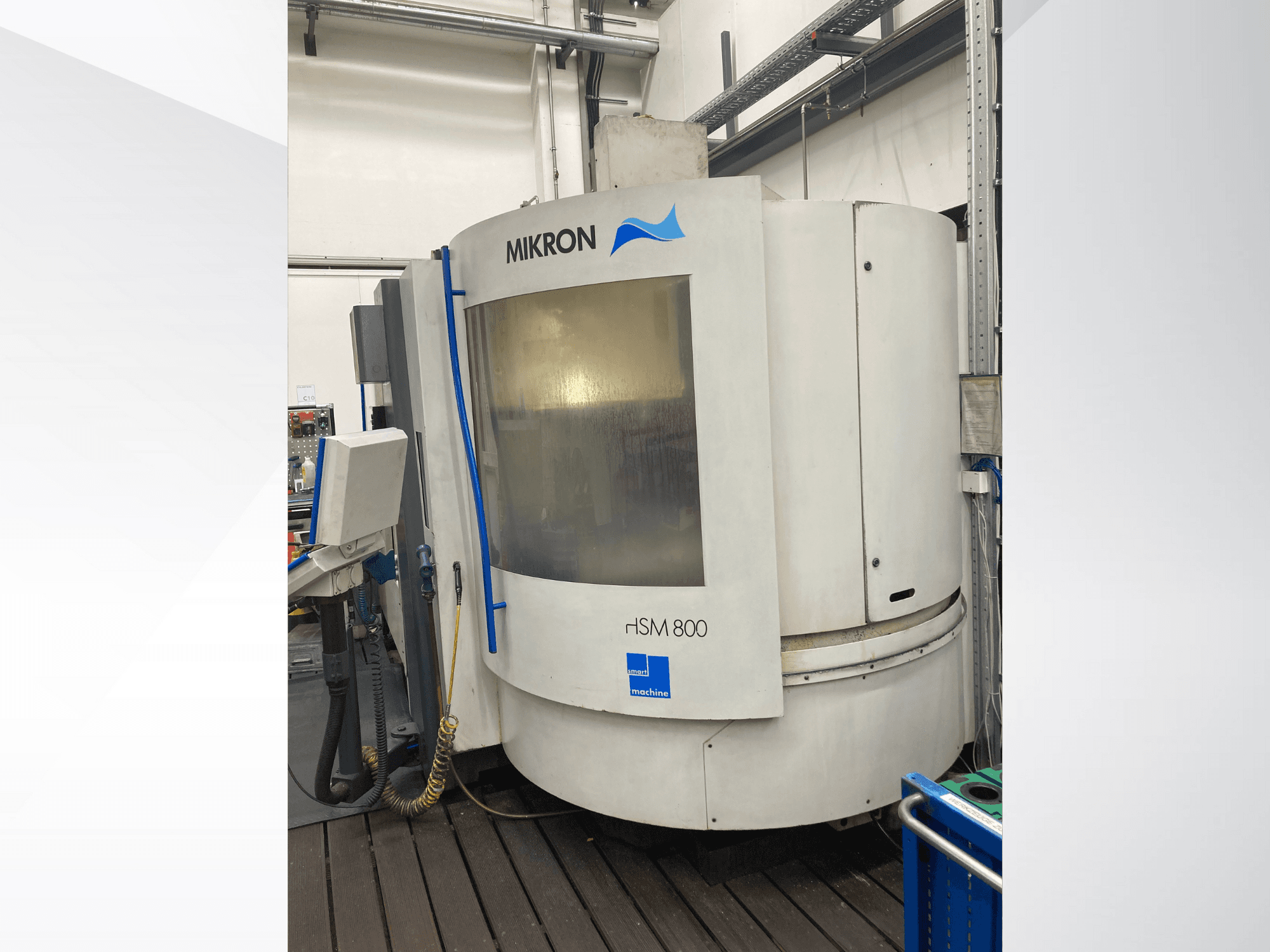 Mikron rISM 800 CNC makinesi, kontrol paneli ile önden görünüm, silindirik tasarım ve mavi vurgular, bir atölye ortamında ayarlanmıştır.