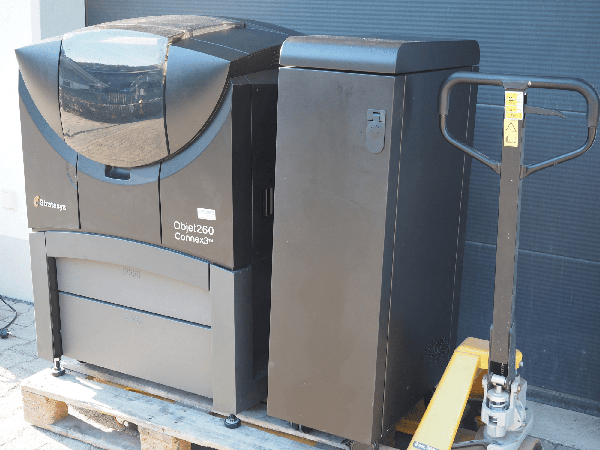 Stratasys Objet260 Connex3 plastik 3D yazıcı, yandan görünüm, kontrol paneli ve bağlı malzeme haznesi ile kompakt tasarıma sahiptir.