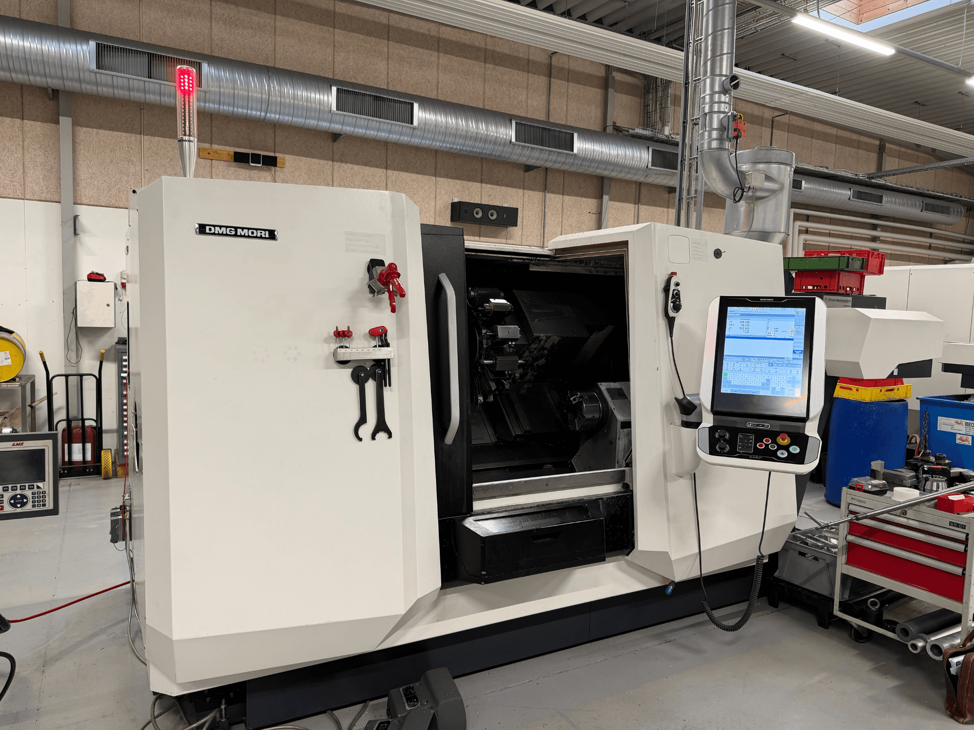 DMG MORI CLX 450 V6 yatay torna tezgahı; kontrol paneli, acil durdurma düğmesi ve güvenlik ışığının görüldüğü önden görünüm.