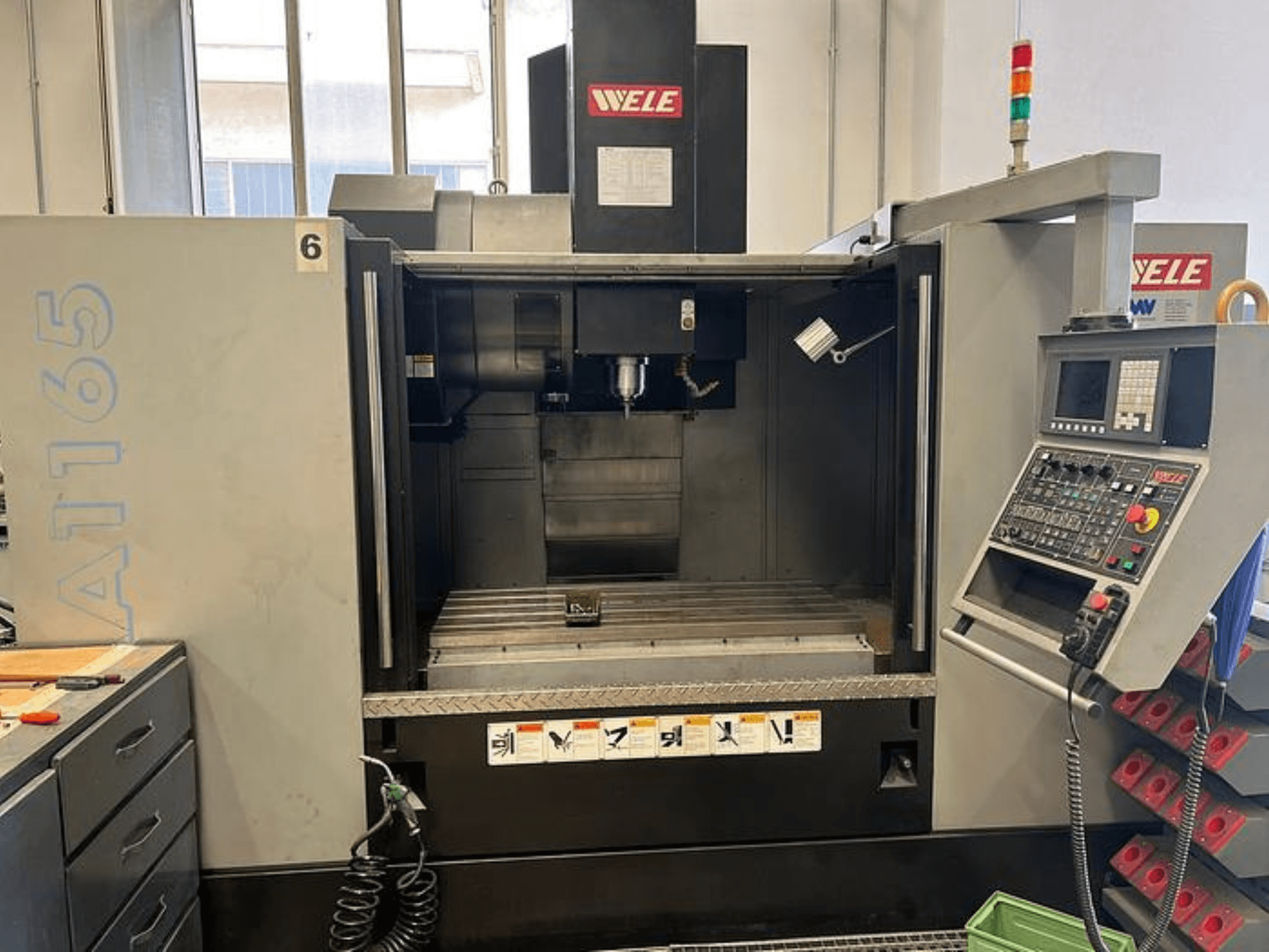 WELE A165 CNC işleme merkezi, önden görünüm, kontrol paneli, takım tutucu ve çalışma masası görünür. Endüstriyel ortam.