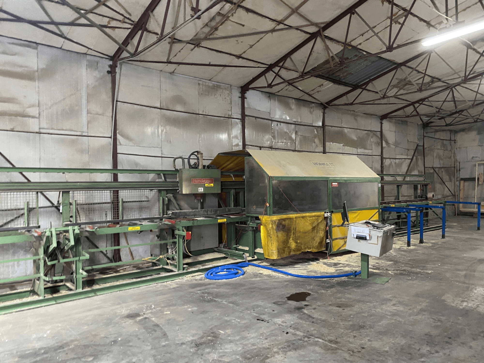 CNC Ahşap İşleme Merkezi HUNDEGGER K1 bir atölyede, makineleri, kontrolleri ve zemindeki talaşı gösteren yandan görünüm.