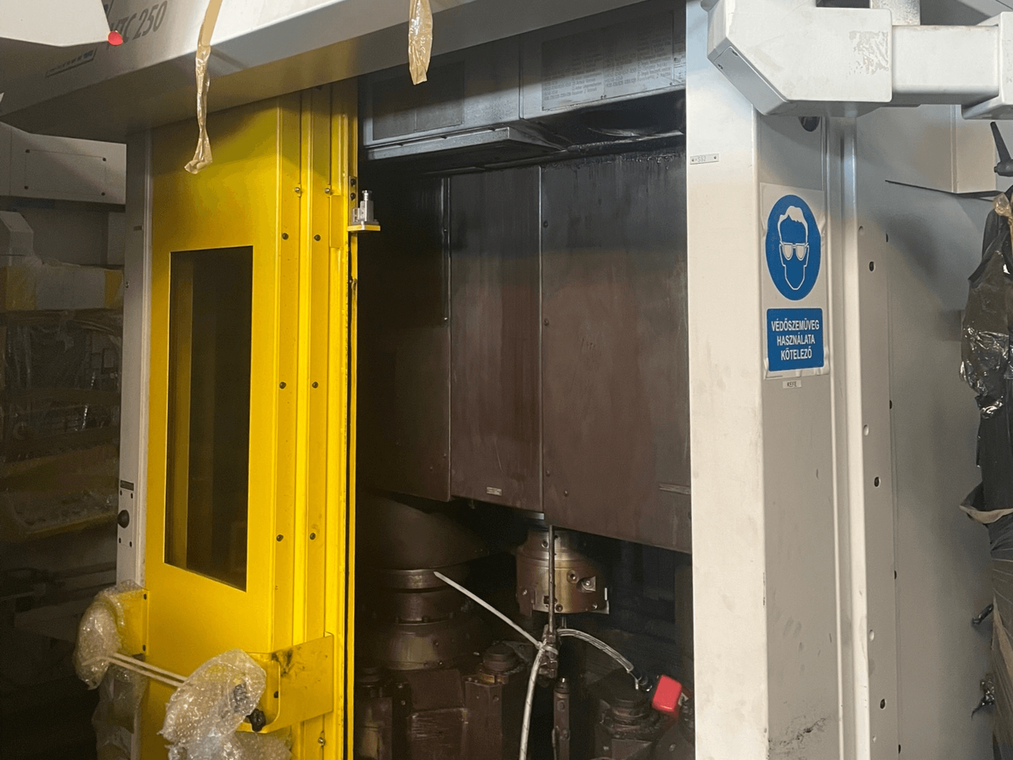 Güvenlik işaretli bir makinenin sarı giriş kapısı, Z250 model endüstriyel bir makinenin önden görünümü, iç bileşenleri gösteriyor.