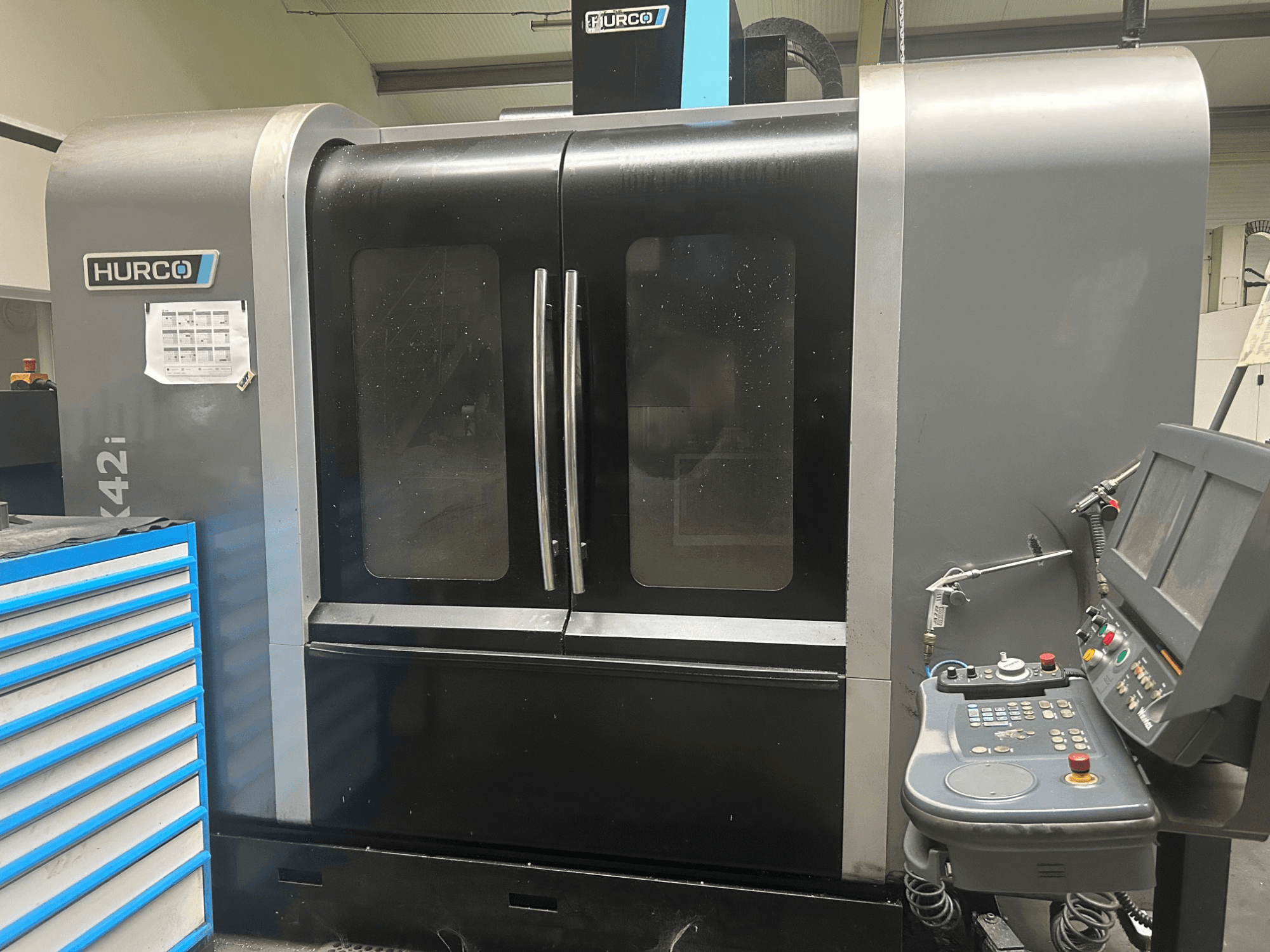 Hurco VMX42i CNC makinesi, yan tarafta kontrol paneli ile önden görünüm, çift kapı ve görünür teknik detaylara sahiptir.