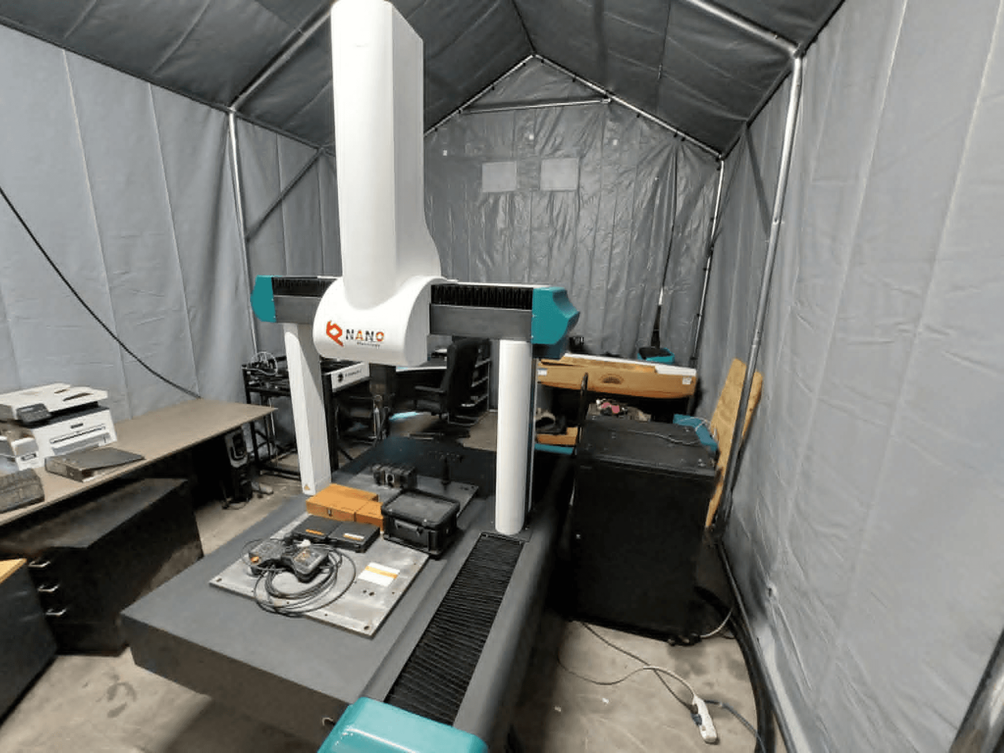 NANO METROLOGY Micr 7106 CMM bir çadırda; makinenin kolunu ve aksesuarlı ölçüm platformunu gösteren önden görünüm.