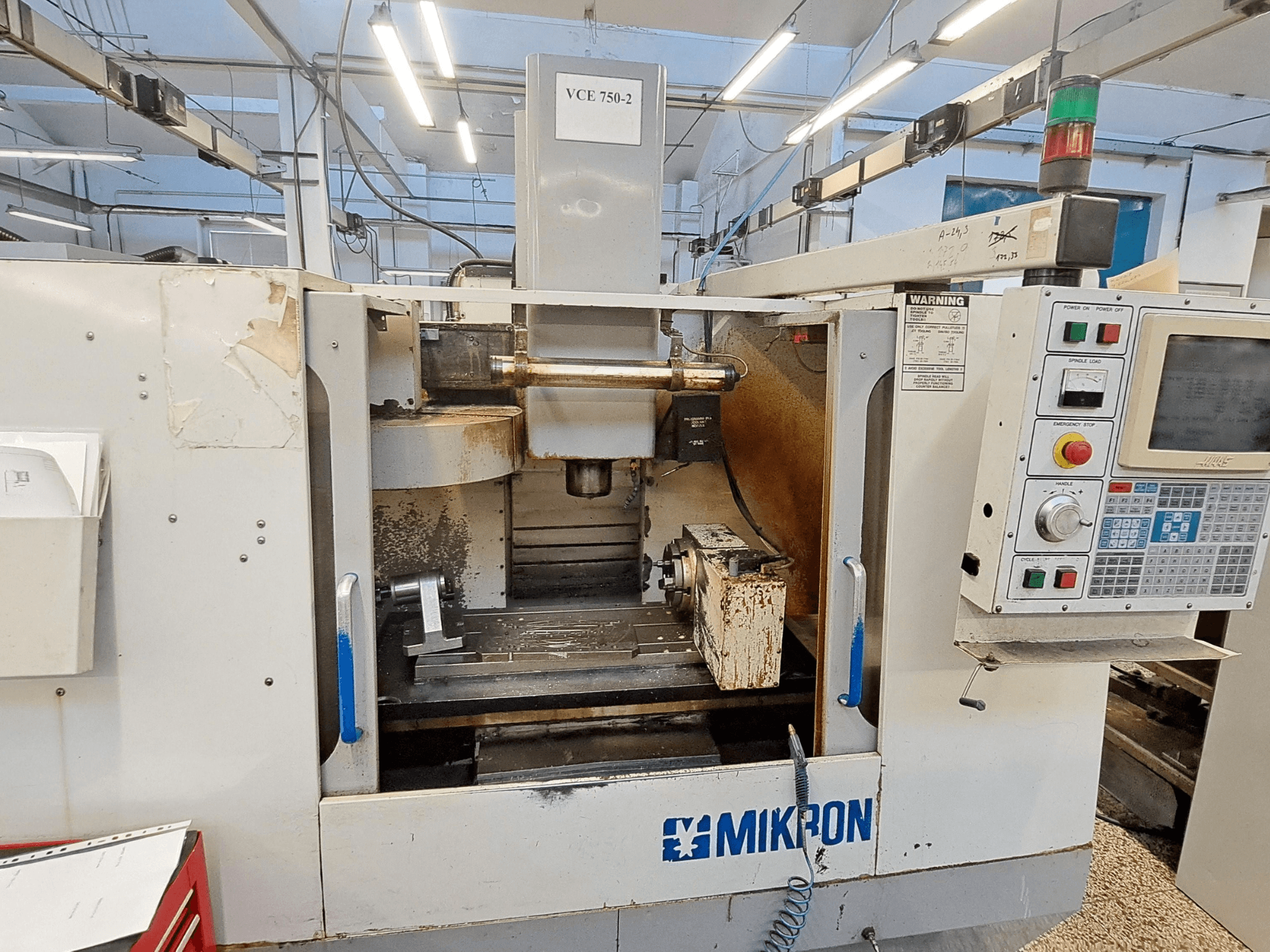 Mikron VCE 750-2 CNC freze makinesi, önden görünüm, kontrol paneli ve işleme alanındaki iş mili, aşınma ve kir gösterir.