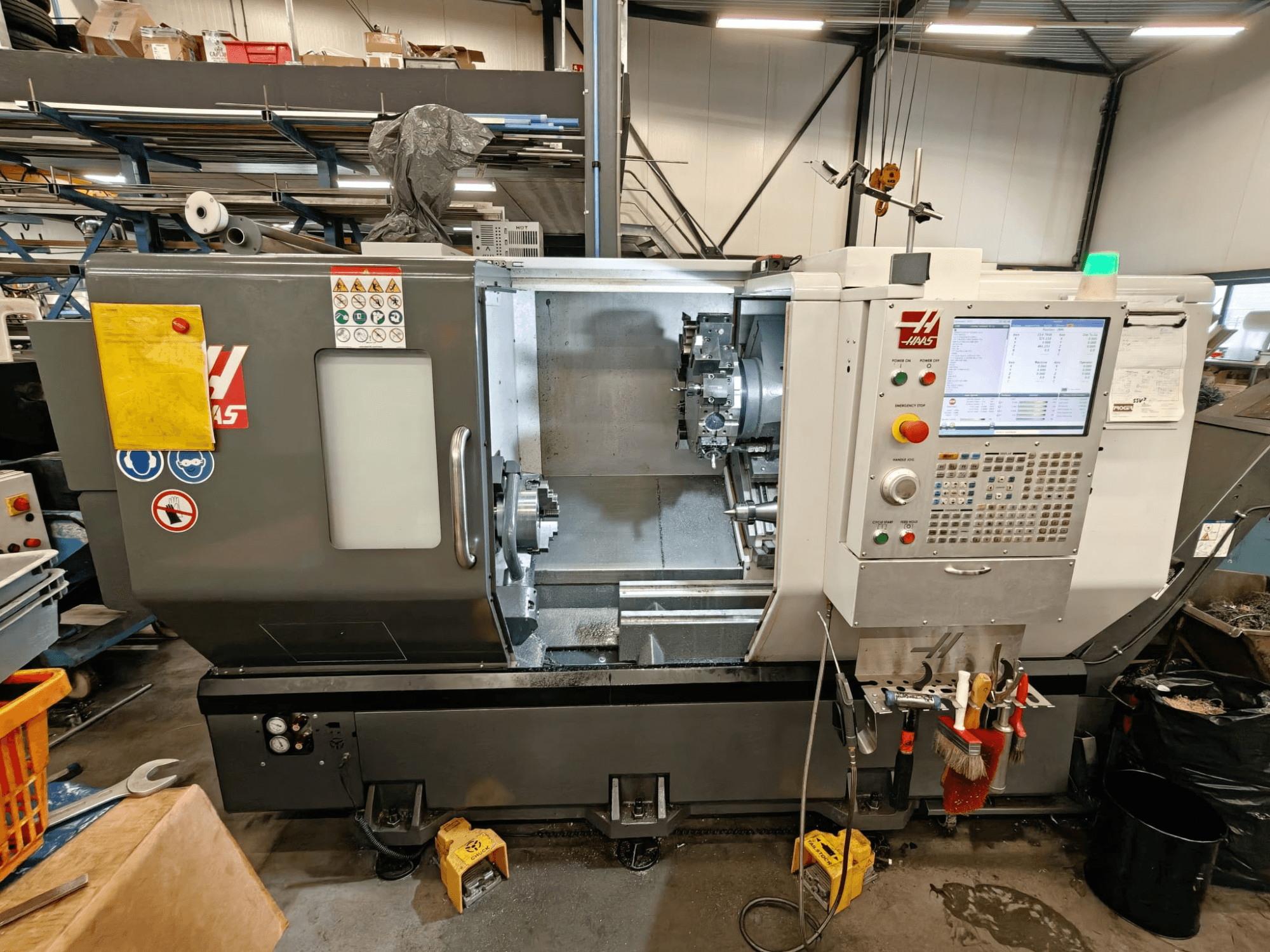 HAAS ST-25Y yatay torna makinesi, önden görünüm, kontrol panelini, takım deposunu ve atölyedeki çalışma düzenini gösterir.