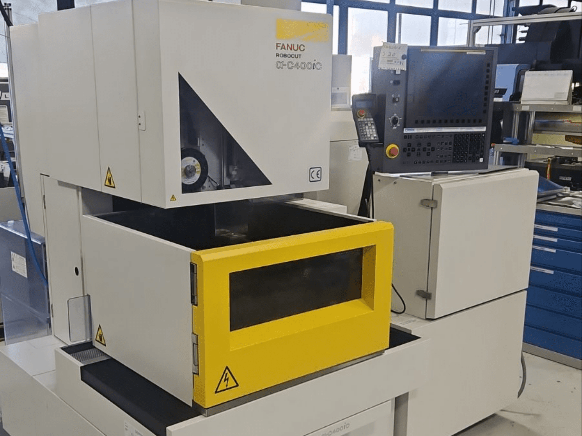 FANUC Robocut alpha-C400iC oyma EDM makinesinin önden görünümü; sarı renkli iş parçası haznesi ve kontrol paneli ile donatılmıştır.