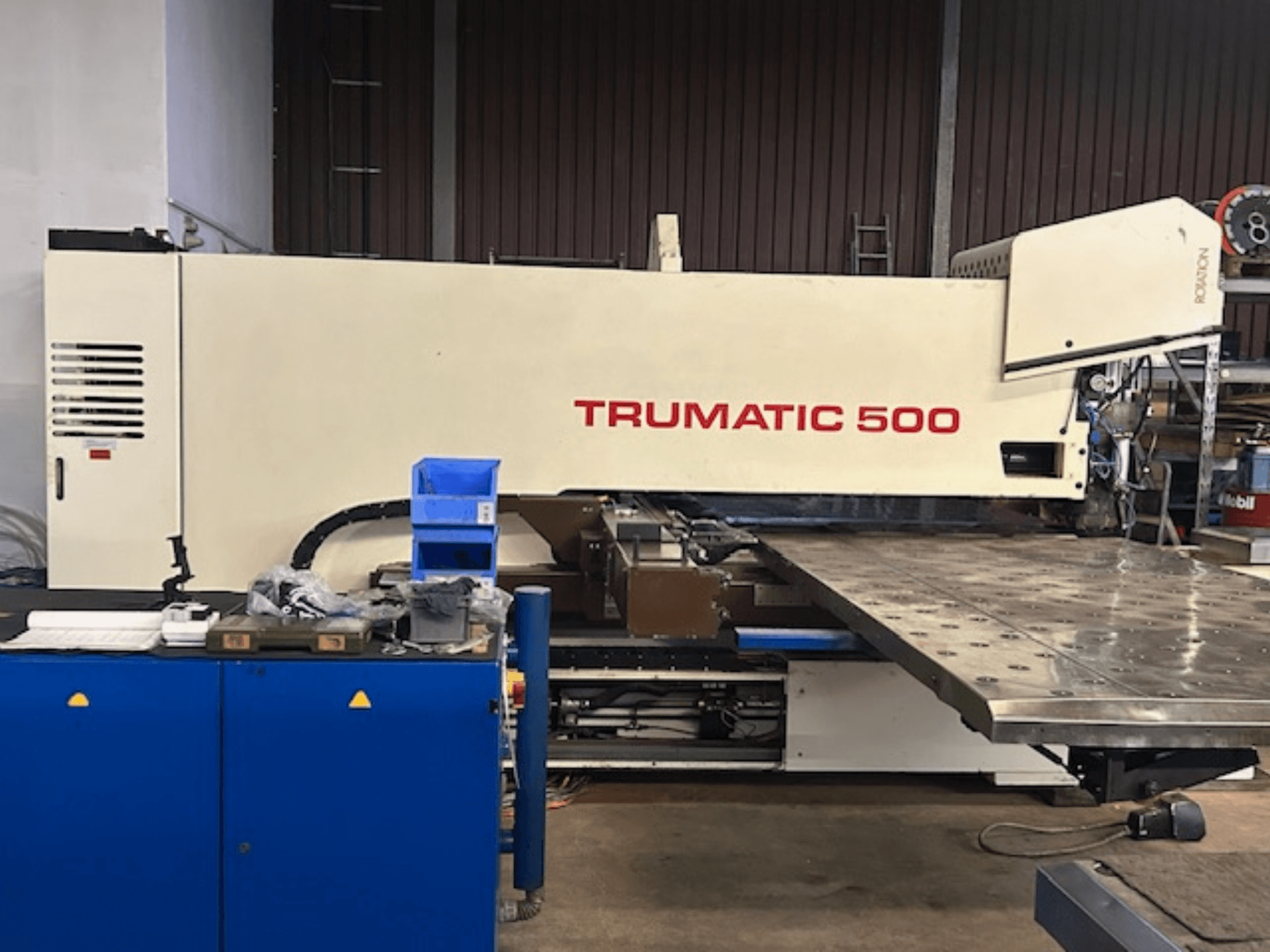 TRUMPF TRUMATIC 500 CNC delme makinesi, önden görünüm, kumanda paneli ve delikli yüzeyi gösteren büyük bir çalışma tezgahı.