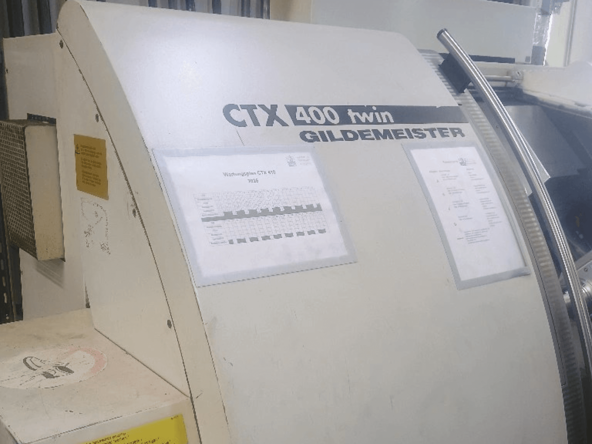 Gildemeister CTX 400 çift yatay torna tezgahı, önden görünüm; kontrol panelleri ve teknik belgeler gösterilmektedir.