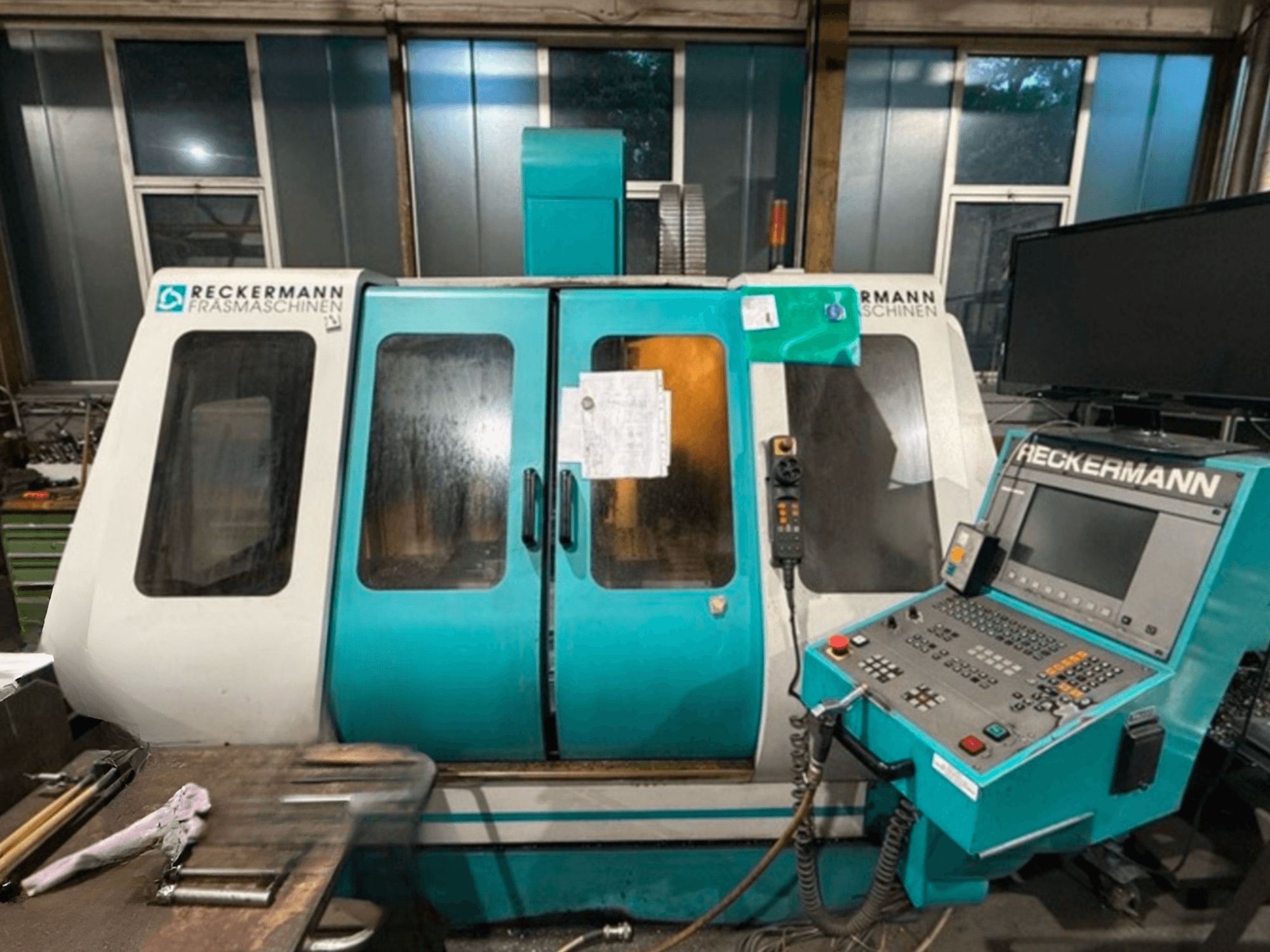 RECKERMANN VMC 850 Üniversal İşleme Merkezi, kontrol paneli ve cam kapıları gösteren önden görünüm.