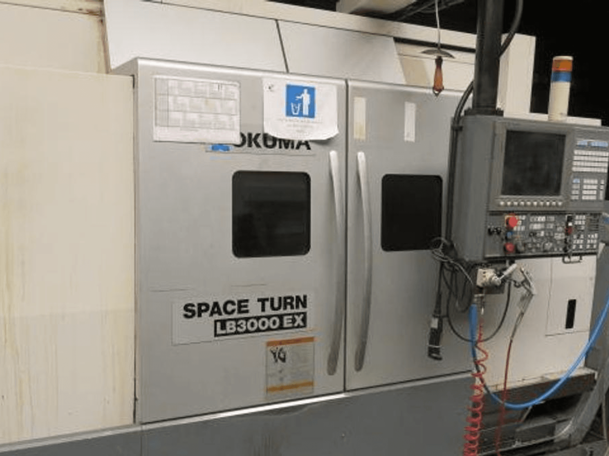 Okuma Space Turn LB3000 EX CNC torna tezgahı, yandan görünüm, kontrol paneli, iki kapı ve görünür kablolar.