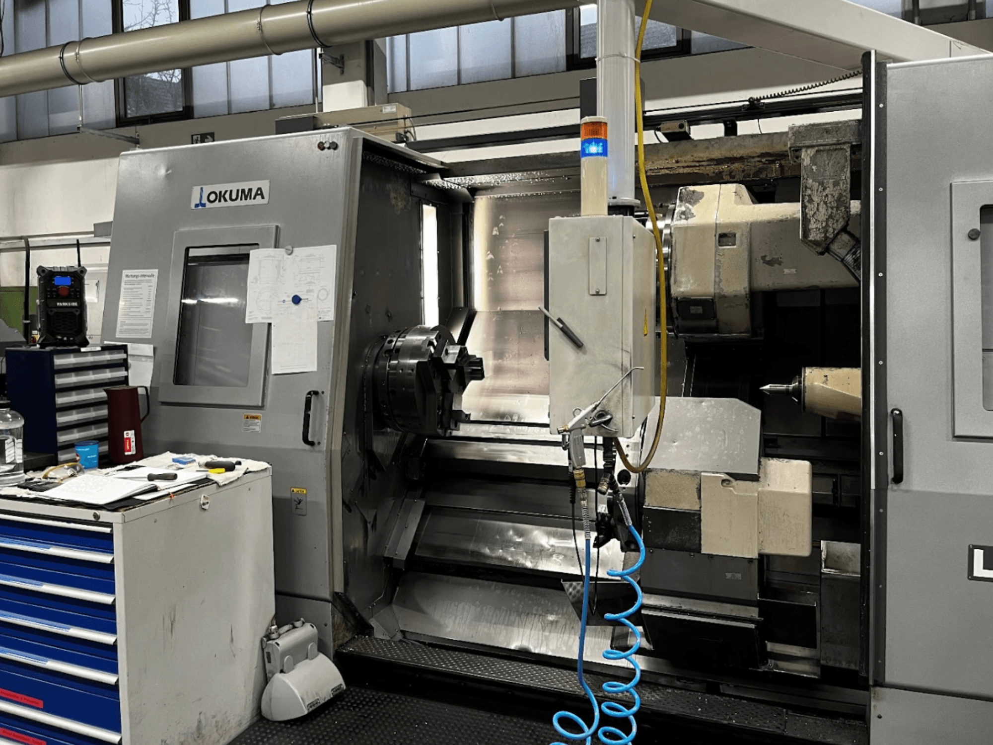 Okuma LU35-M yatay torna makinesi, önden görünüm. Kontrol paneli, takımlar ve işleme operasyonları için büyük ayna.